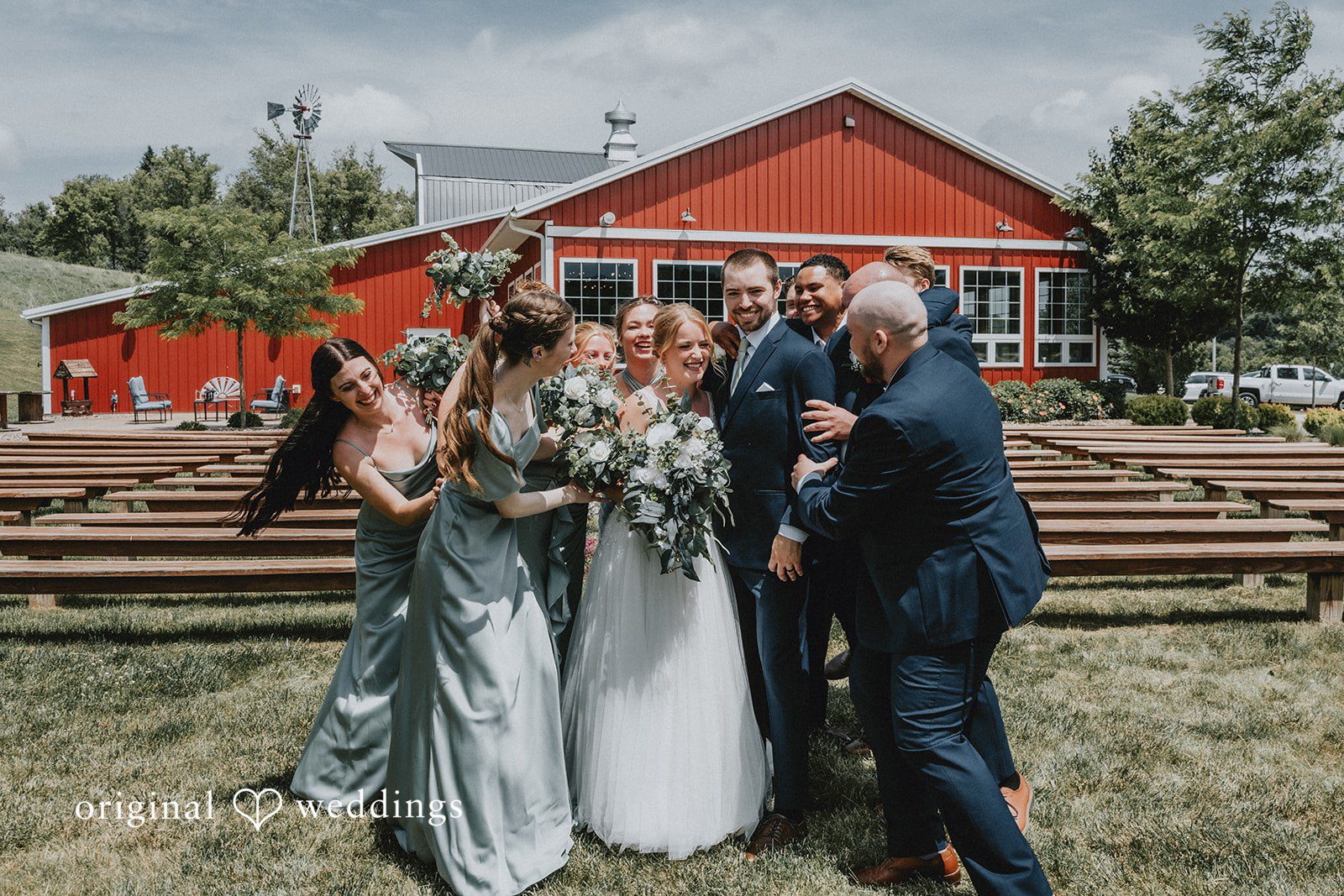 Neil + Hallie A wedding party gathering and celebrating together in front of a red building.