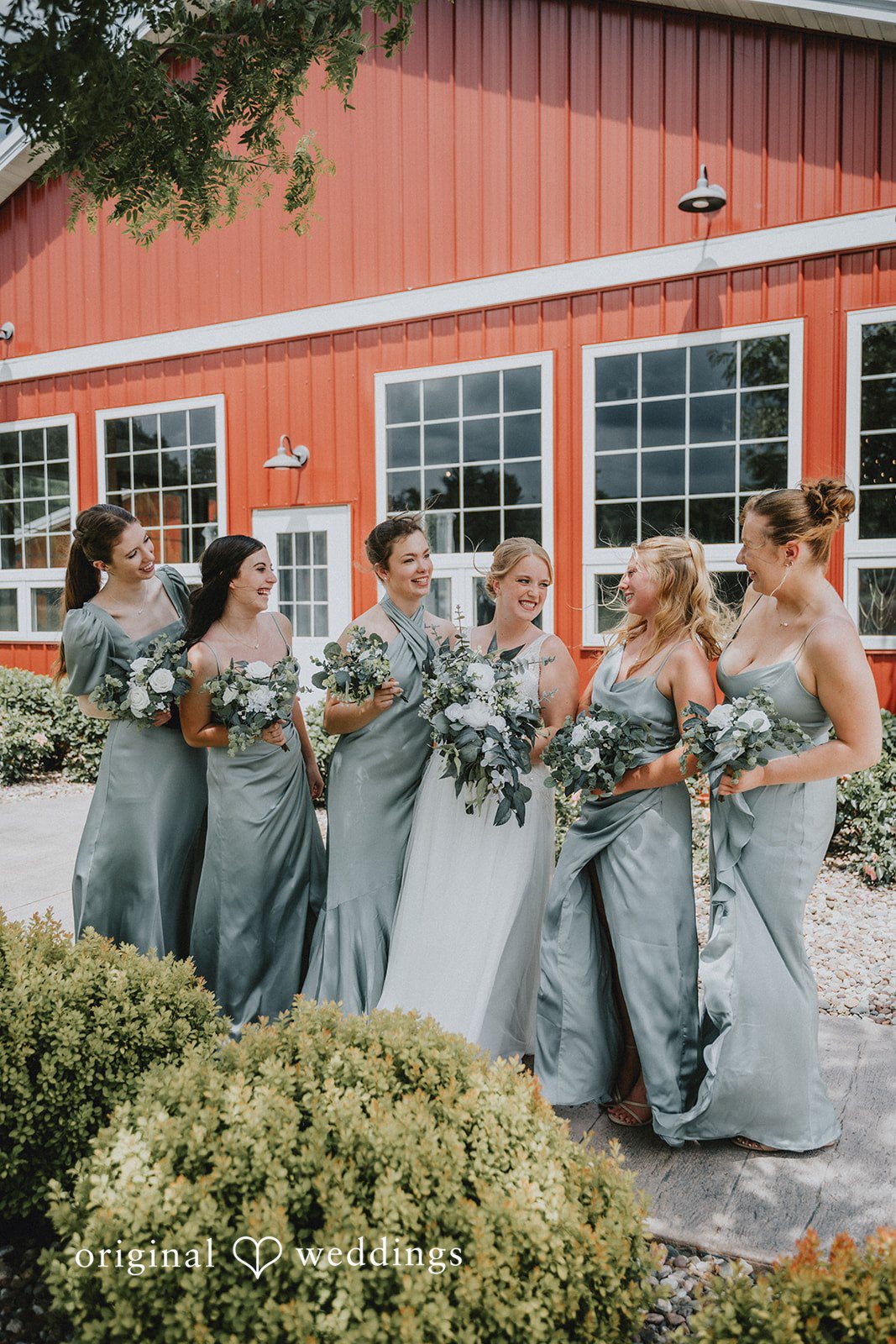 Neil + Hallie Bride and bridesmaids in dusty blue dresses standing in a row in a garden.