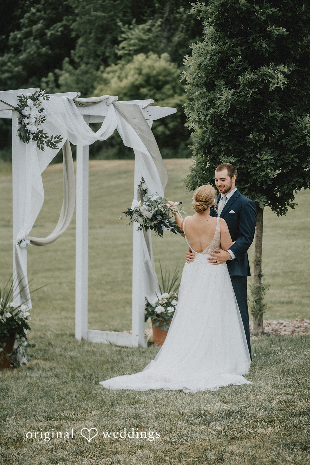 Neil + Hallie A bride and groom standing together at the altar under a white arch structure.