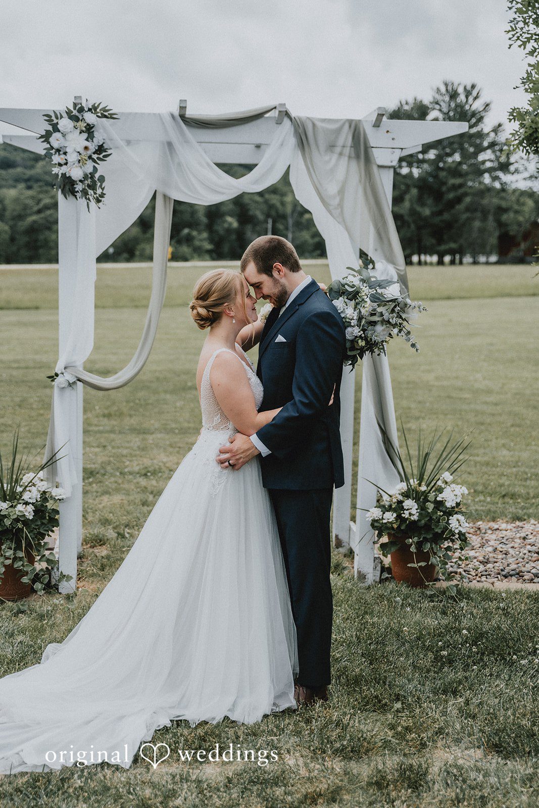 Neil + Hallie A bride and groom sharing a romantic embrace on a field after the ceremony.