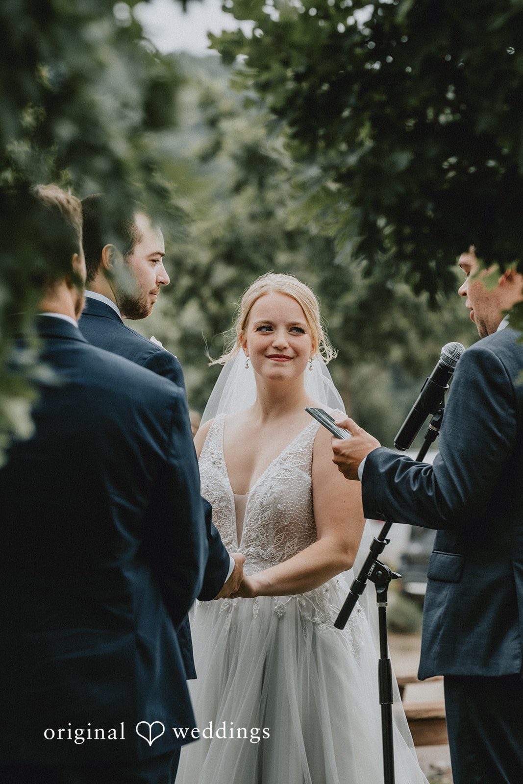 Neil + Hallie A couple facing each other during their wedding ceremony as an officiant reads.
