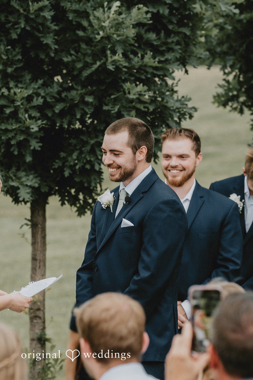 Neil + Hallie A groom and groomsman smiling together before the wedding ceremony begins.