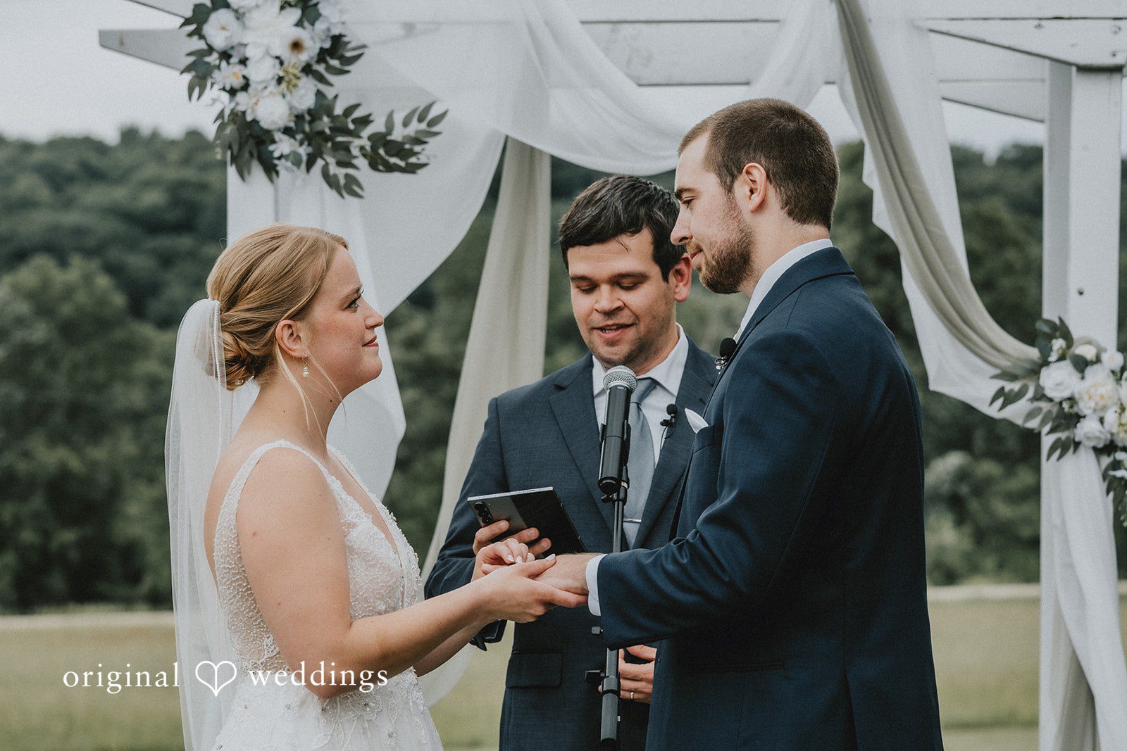 Neil + Hallie A bride and groom holding hands while exchanging vows at the altar.