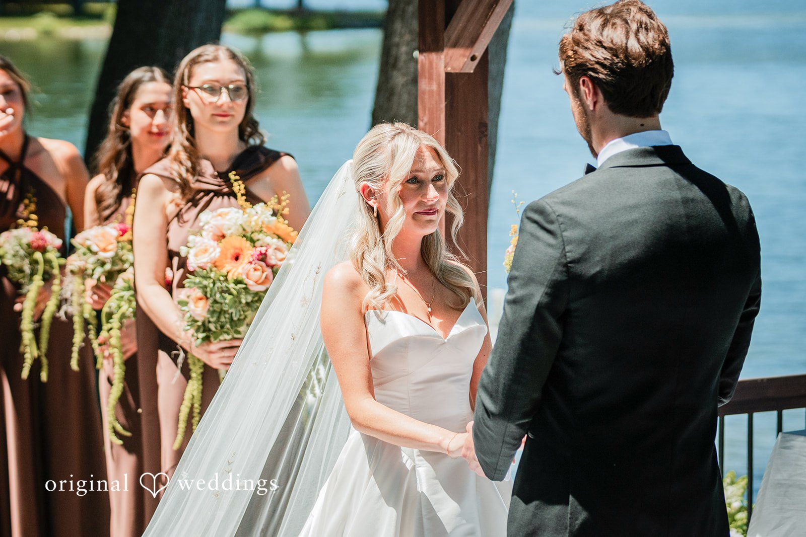 Trey + Bailey Bride holding the groom's hands during an emotional waterfront ceremony