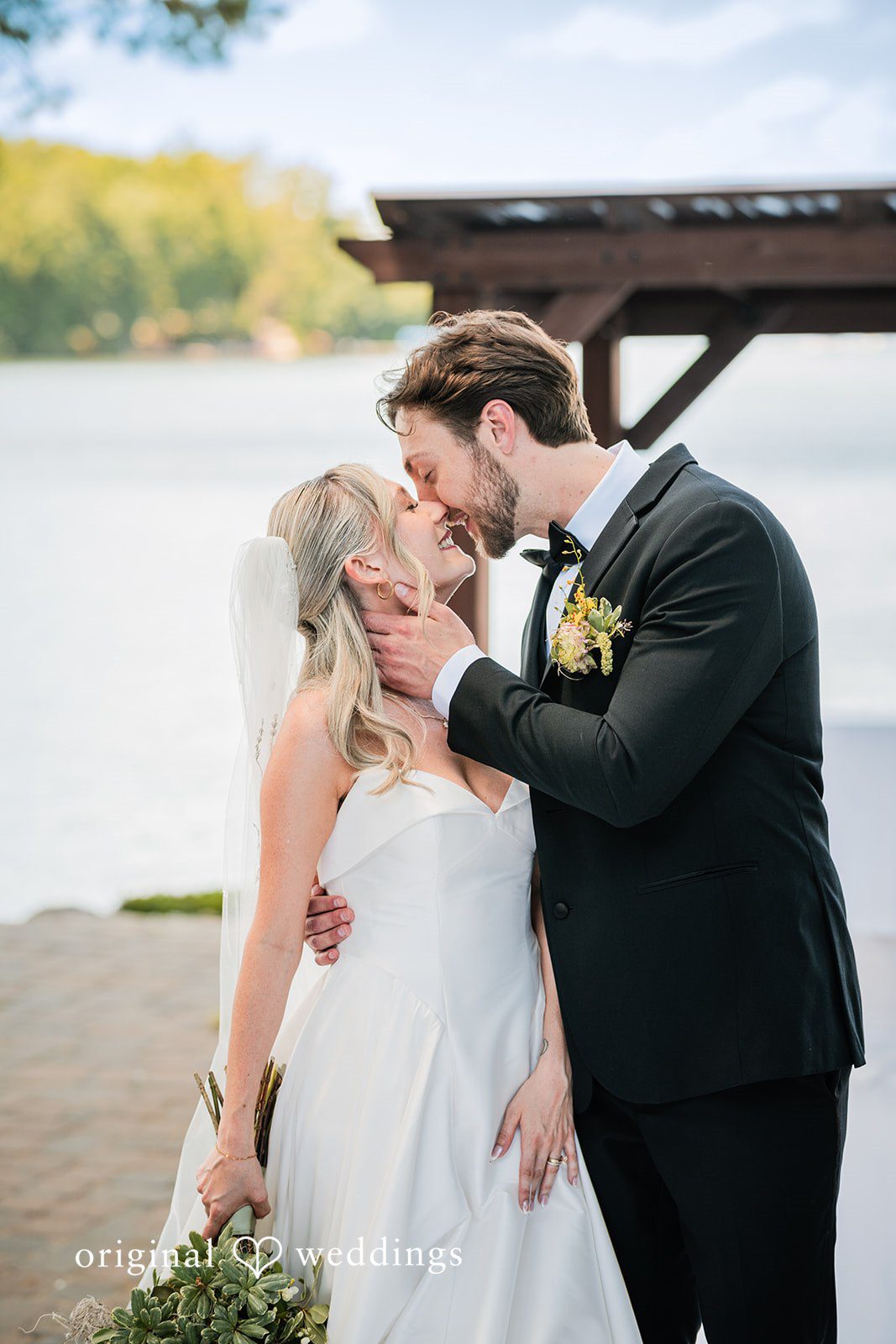 Trey + Bailey Romantic newlywed kiss beside the waterfront