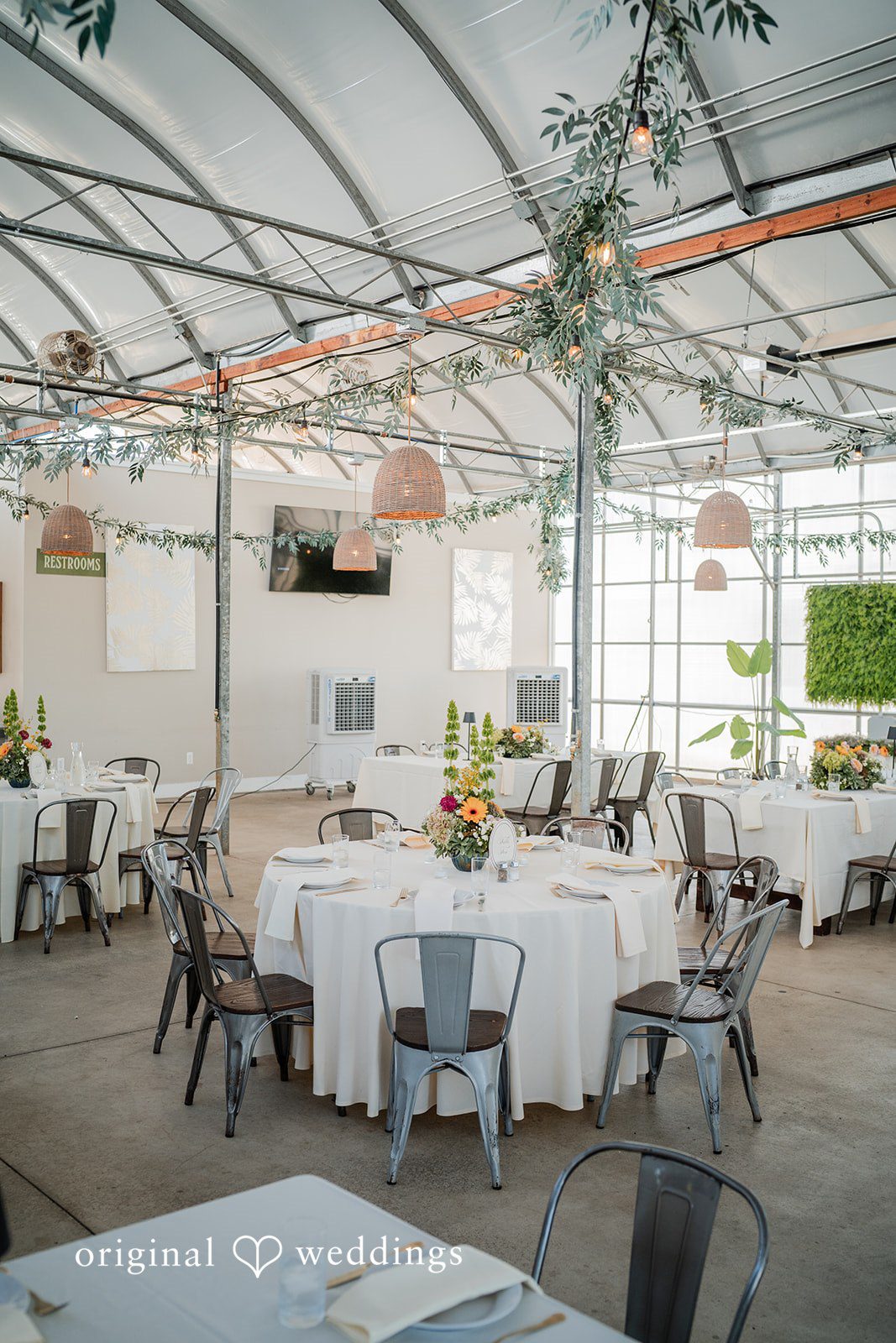 Trey + Bailey Reception hall decorated with hanging greenery and round tables at Blake's Backyard