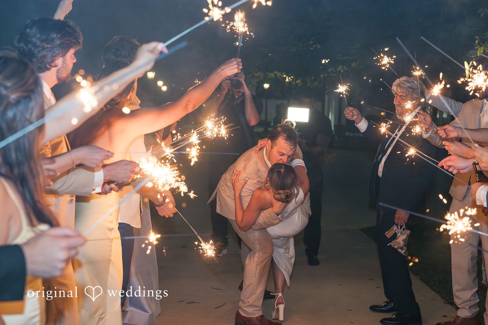 Brett + Ava Bride and groom sharing a kiss with guests cheering around