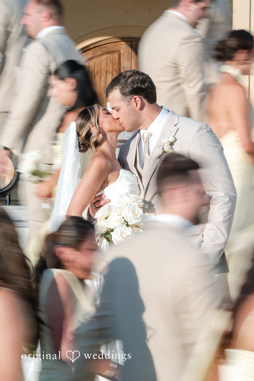 Brett + Ava Bride and groom sharing a romantic kiss with guests around