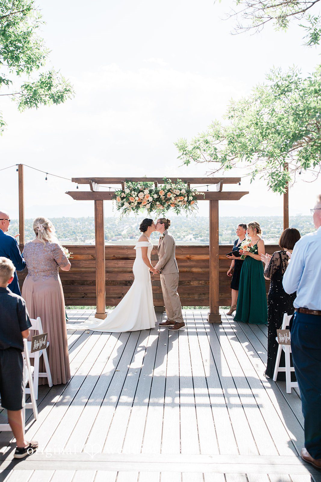 Rachel & Krystal Couple sharing a kiss at the end of the aisle while guests watching.