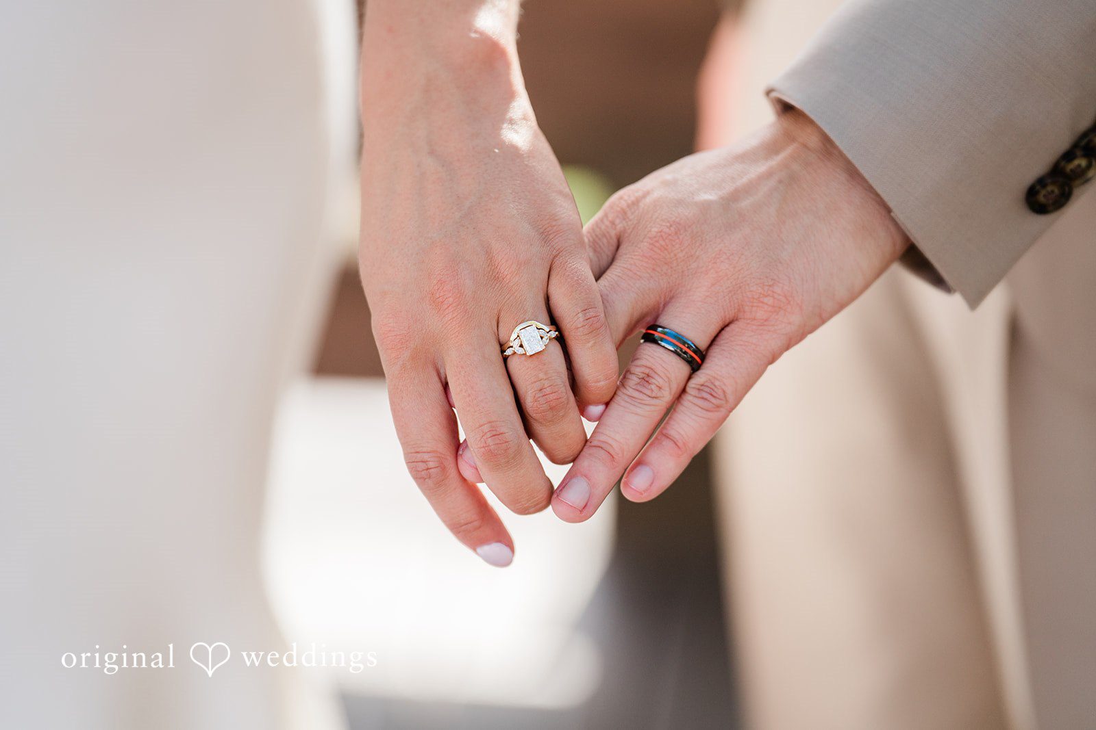 Rachel & Krystal A close-up view of a couple holding hands to showcase their wedding rings.