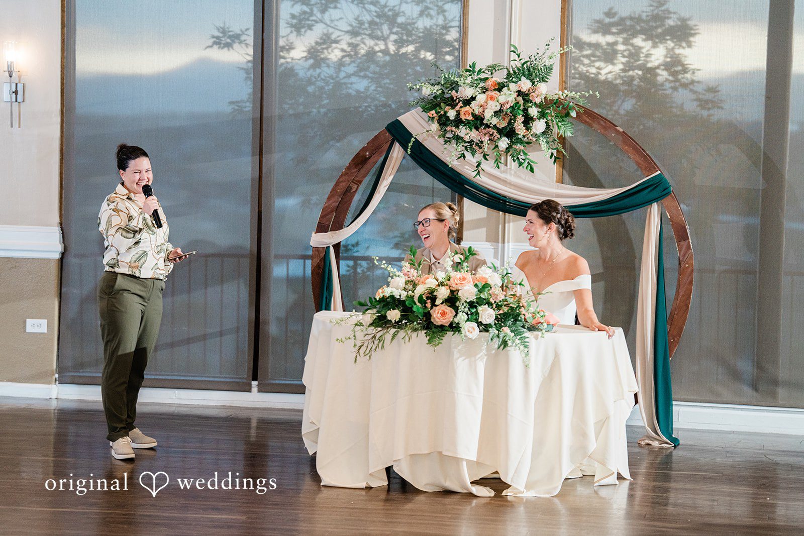 Rachel & Krystal A wide shot of a reception table set up with floral decorations.