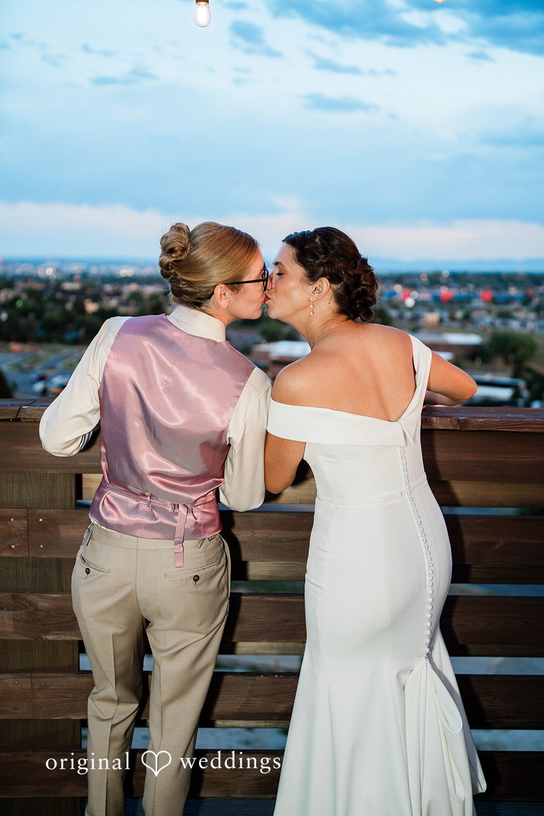 Rachel & Krystal A wedding couple sharing a kiss with their backs to the camera.