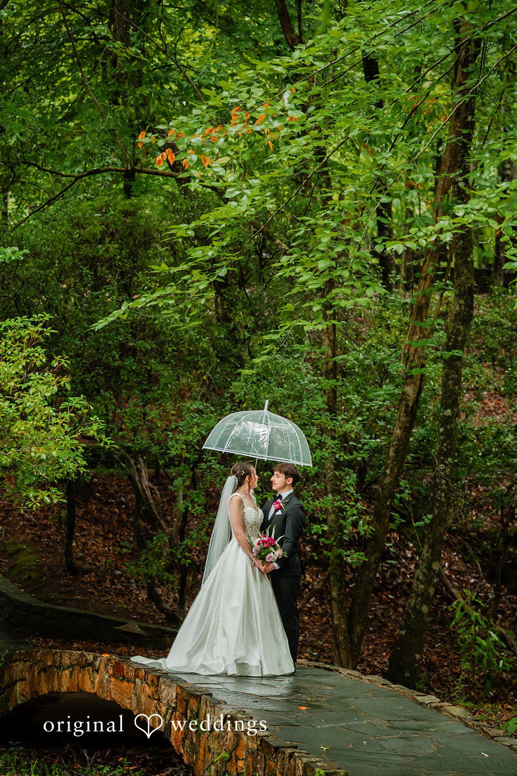 Jacob + Jadee Rainy wedding portrait on the stone bridge near Callaway Gardens Ida Memorial Chapel.