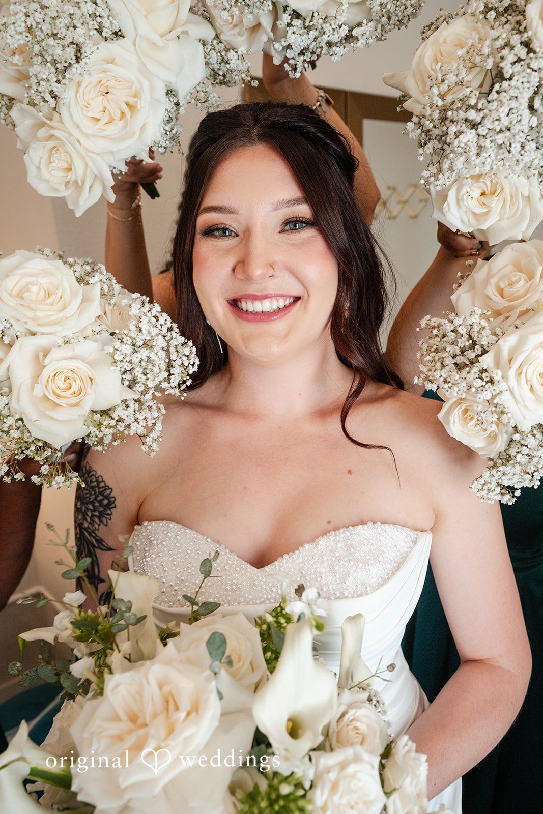 Noah + Jade Close-up portrait of a smiling bride holding a bouquet of white roses.