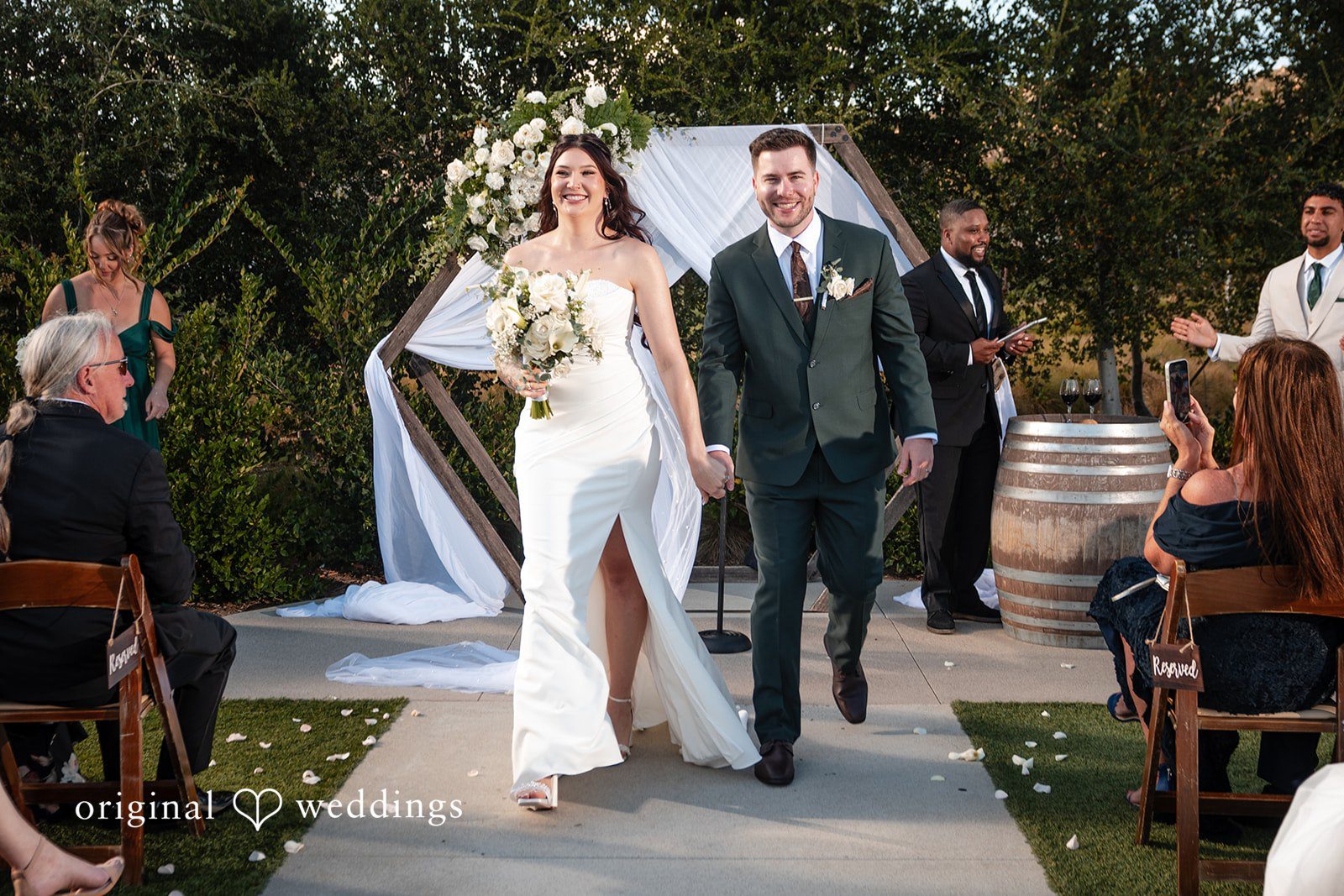 Noah + Jade A smiling bride and groom walking down the aisle hand-in-hand after their ceremony.