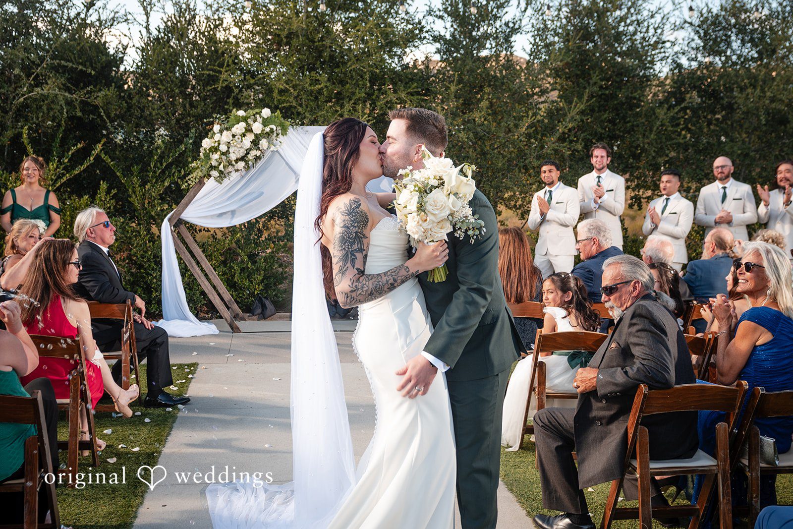 Noah + Jade A bride and groom sharing a kiss at the altar in front of their wedding guests.