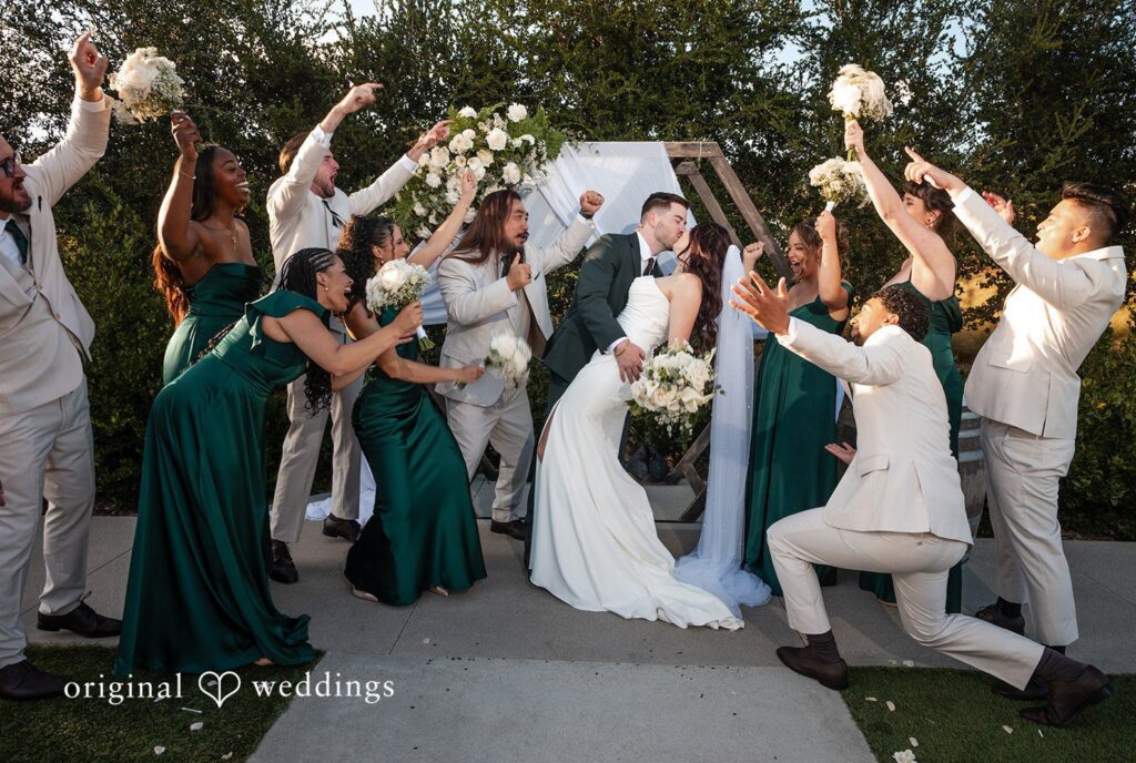 Noah + Jade Wedding party members throwing petals and cheering as the bride and groom kiss.