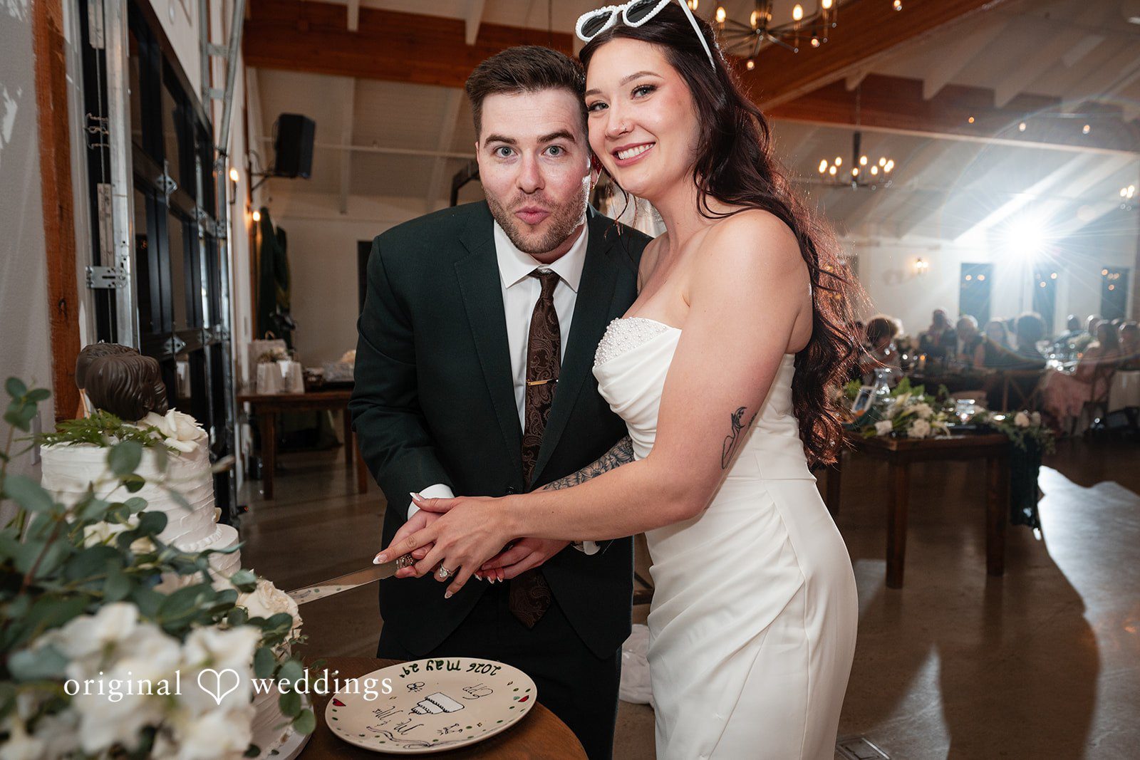 Noah + Jade A bride and groom smiling as they cut their wedding cake together.