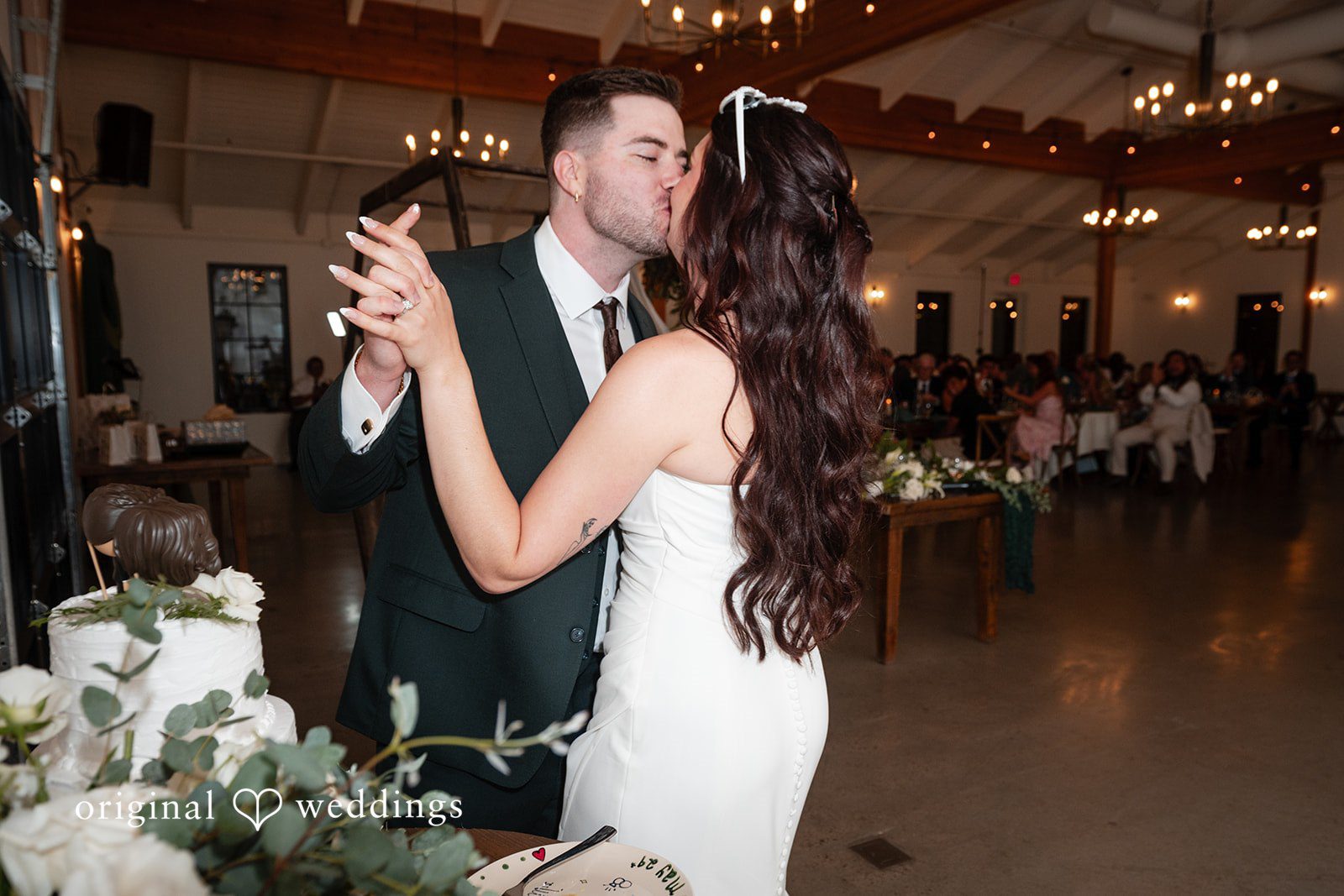 Noah + Jade A bride and groom sharing a slow dance next to their wedding cake.