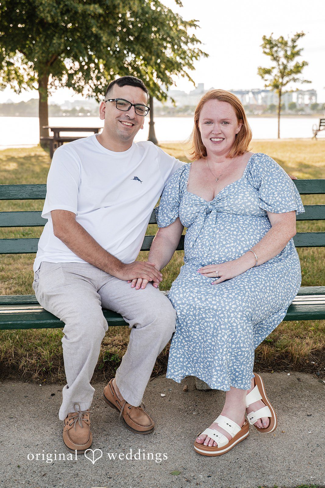 Kelly + Geoffrey A happy couple sitting closely together and smiling on a park bench during their photo session.