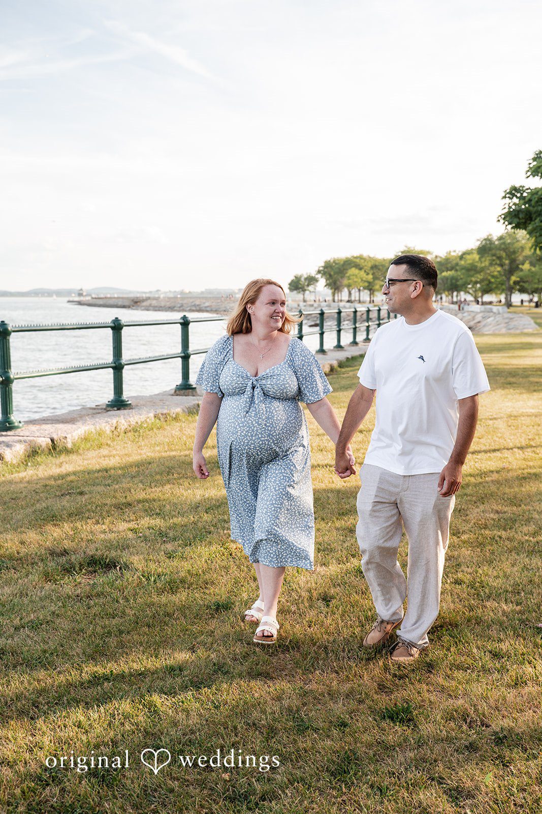 Kelly + Geoffrey Couple walking hand-in-hand on a grassy path.