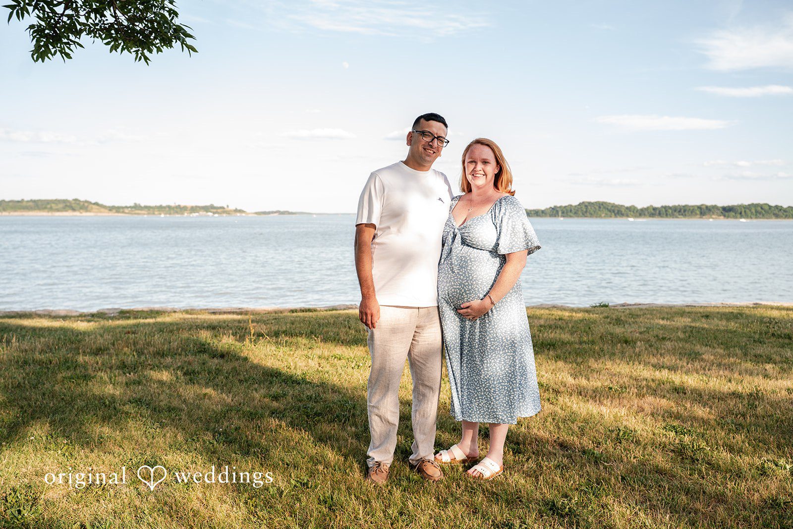 Kelly + Geoffrey Couple standing together in a field by water at Castle Island.