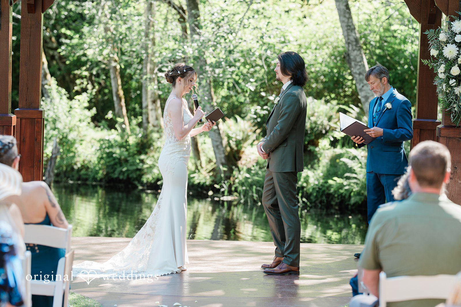 Jennifer + Steven Bride looking at the book while the groom looks at her as they stand before the priest at cedar springs.