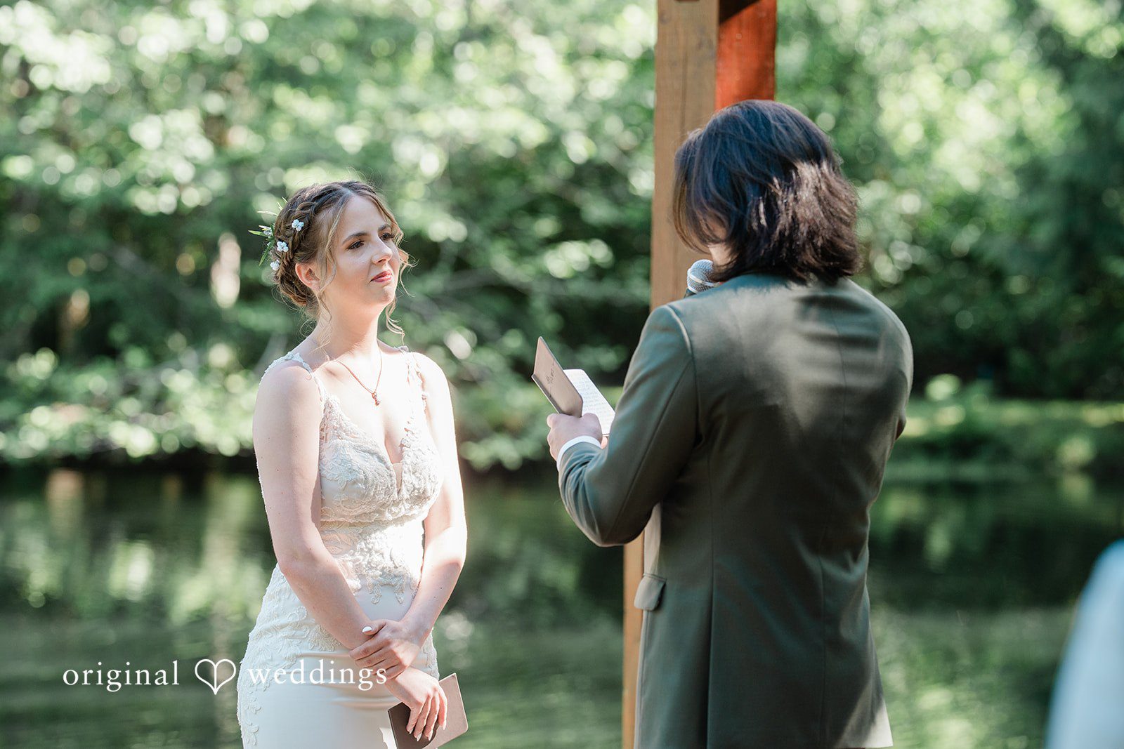 Jennifer + Steven Groom looking at the book while the bride looks at him as they stand before the priest at cedar springs .