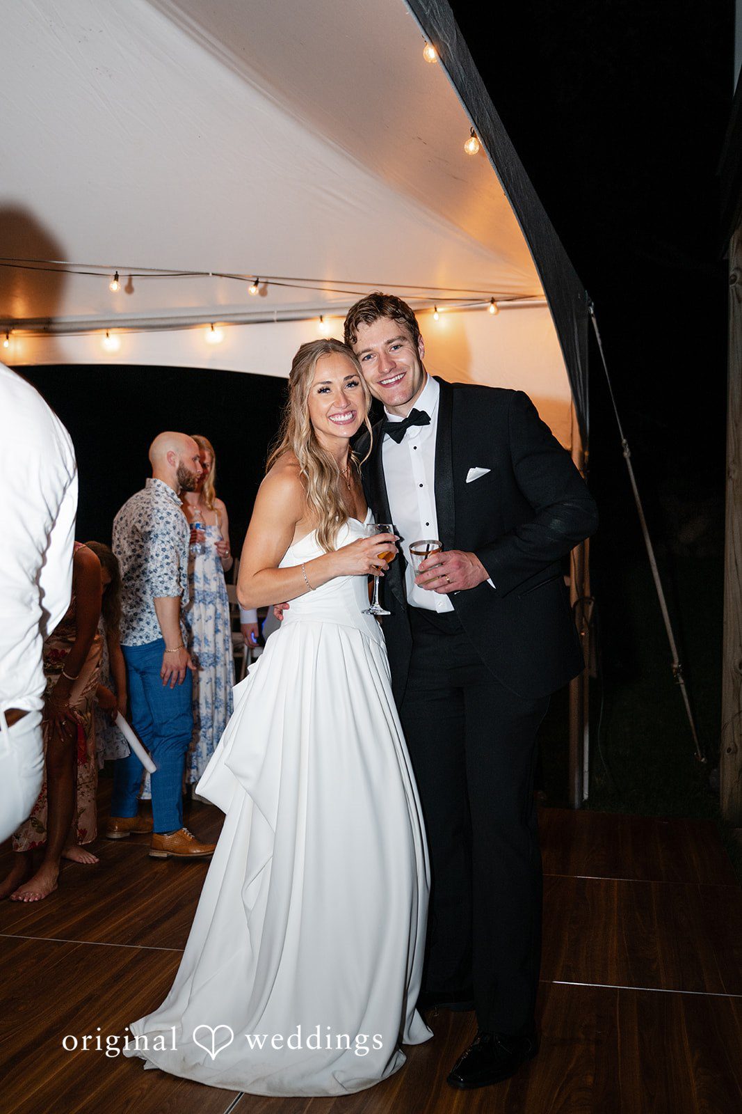 Brandi + Ryan Bride and groom smiling together while holding drinks during the wedding reception.