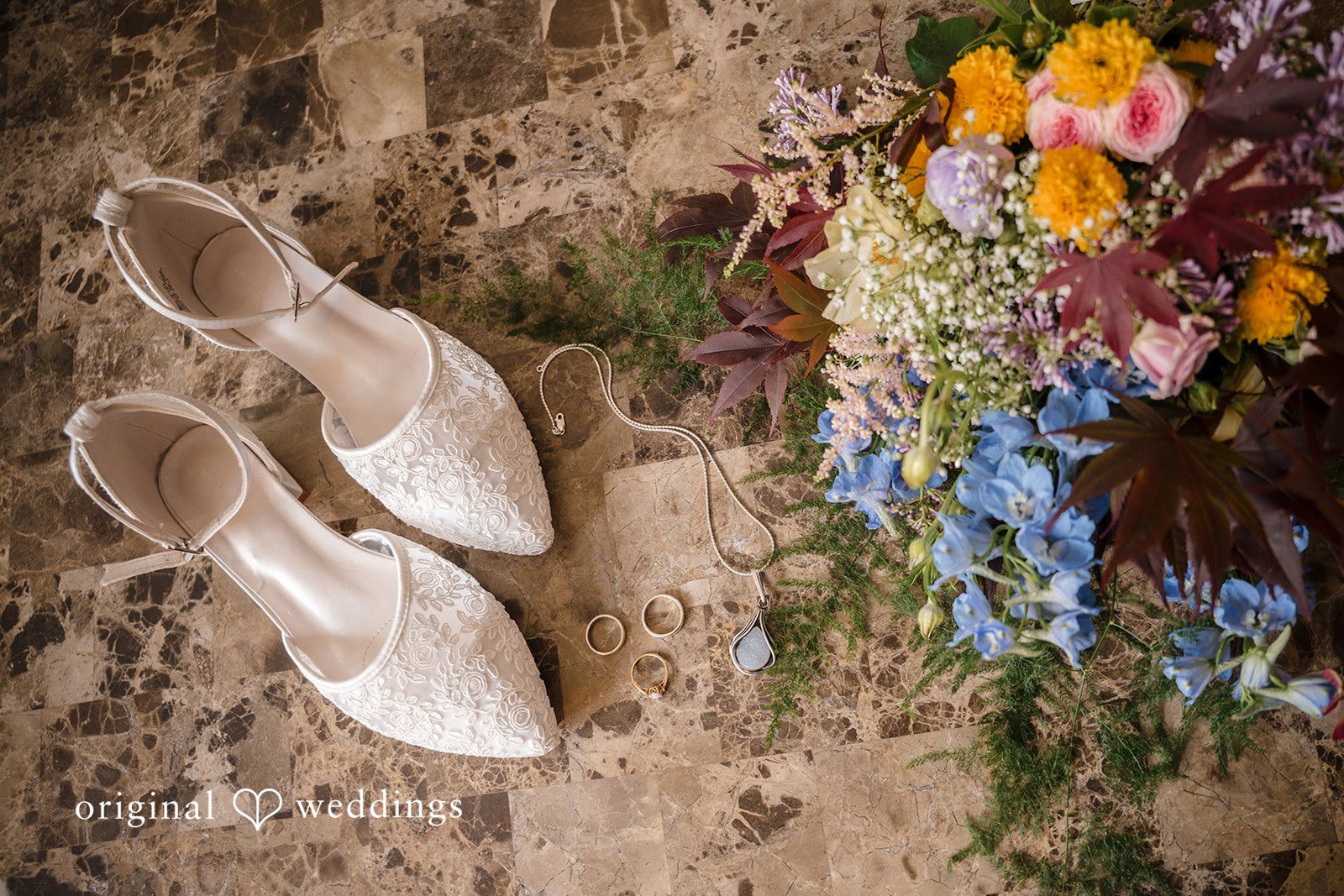 Meghan + Rowan A pair of elegant white bridal heels positioned next to a colorful wedding bouquet.