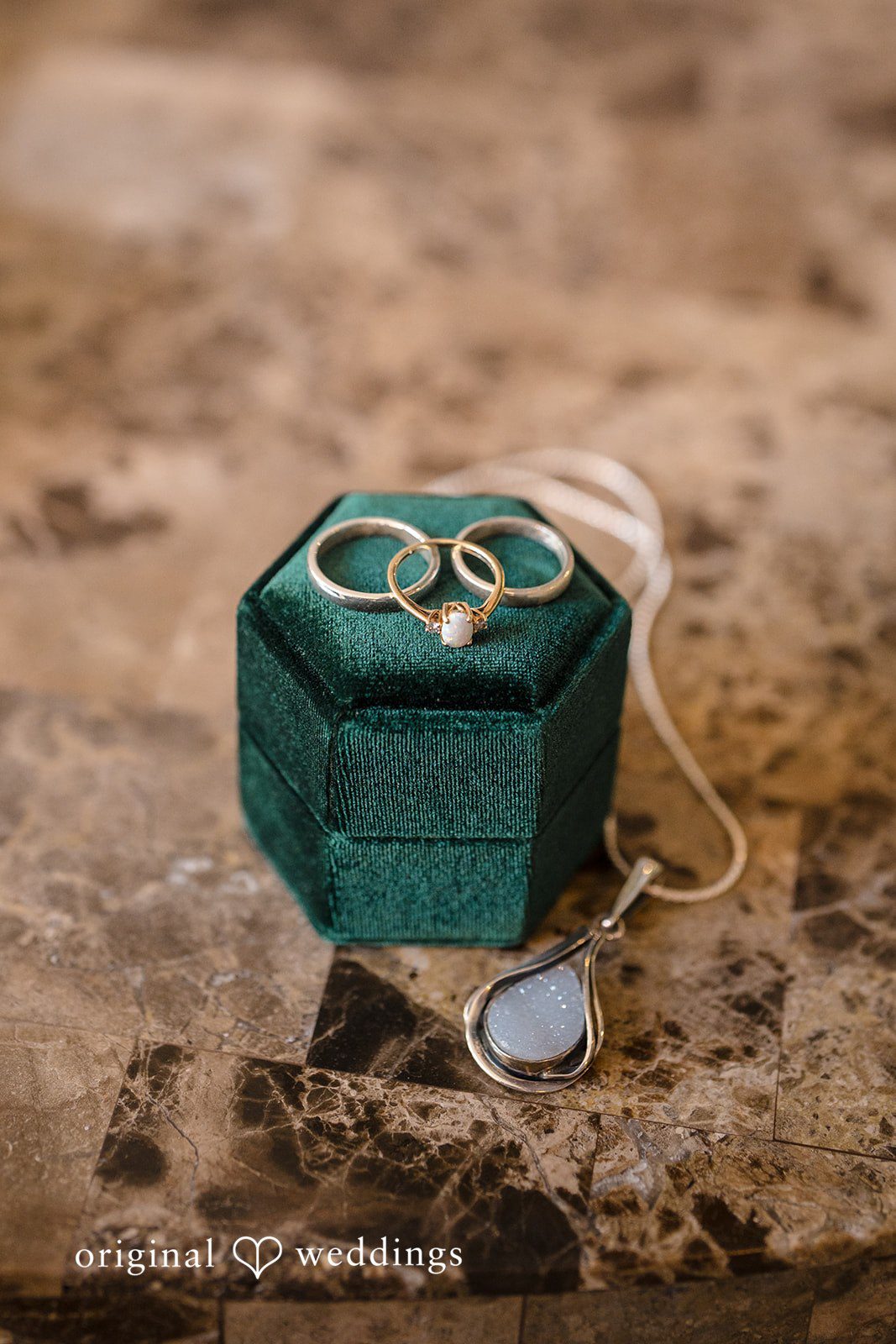 Meghan + Rowan A pair of gold wedding bands sitting on top of an open, dark green velvet ring box.