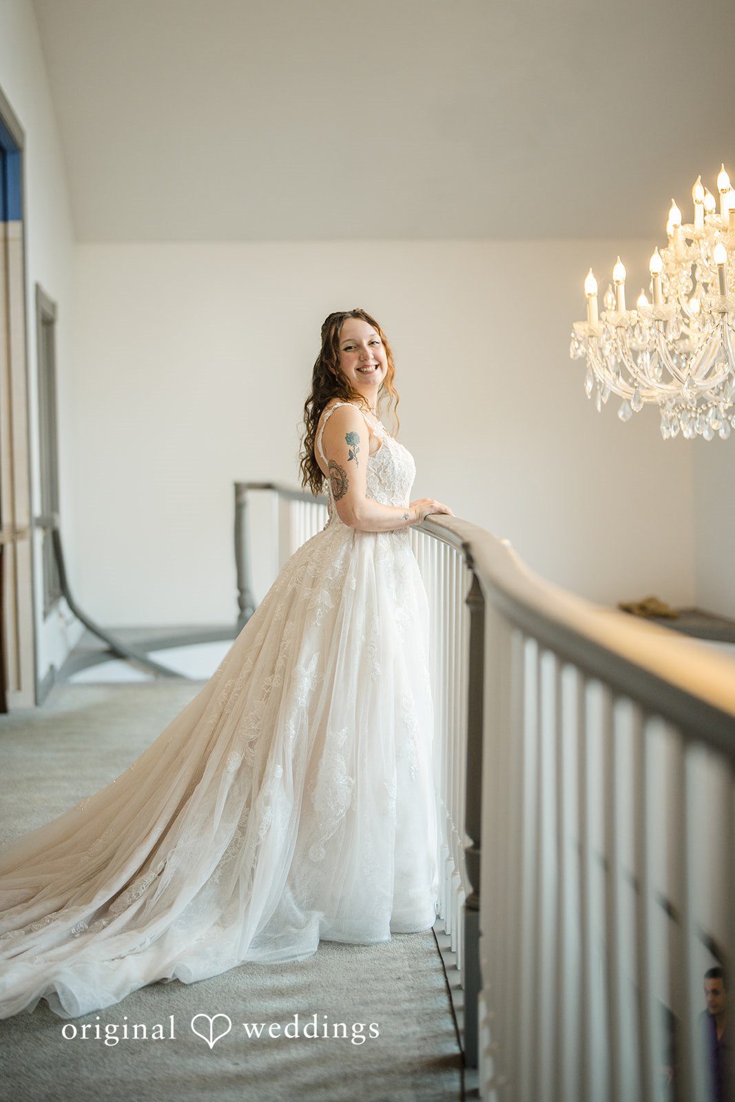 Meghan + Rowan A bride in a long, flowing white gown standing at the top of a grand staircase.
