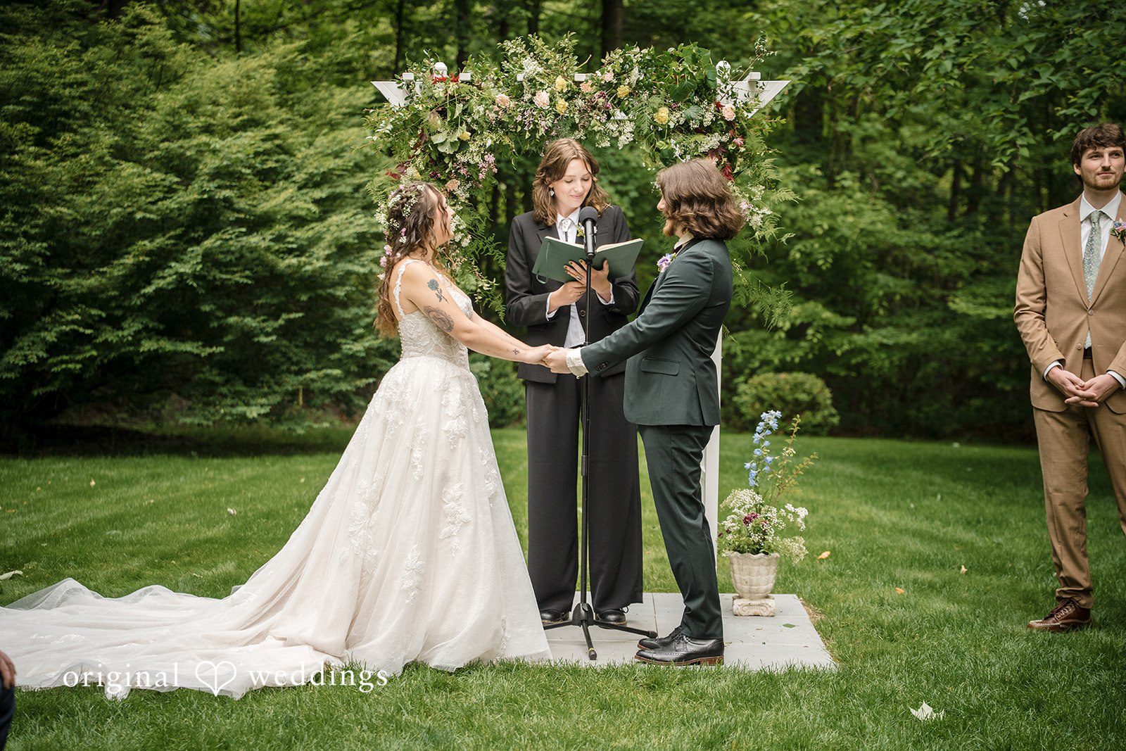 Meghan + Rowan A bride and groom holding hands in front of an officiant during a wedding ceremony.