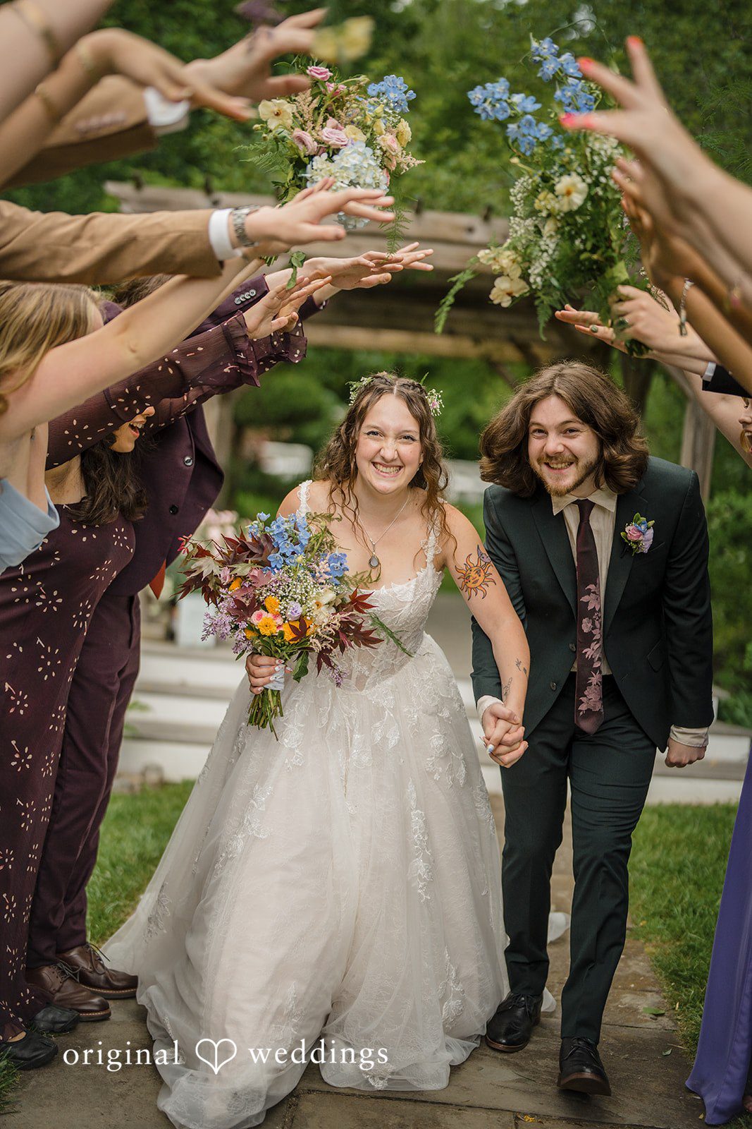 Meghan + Rowan A newly married bride and groom holding hands and walking down the aisle as guests toss petals over them.