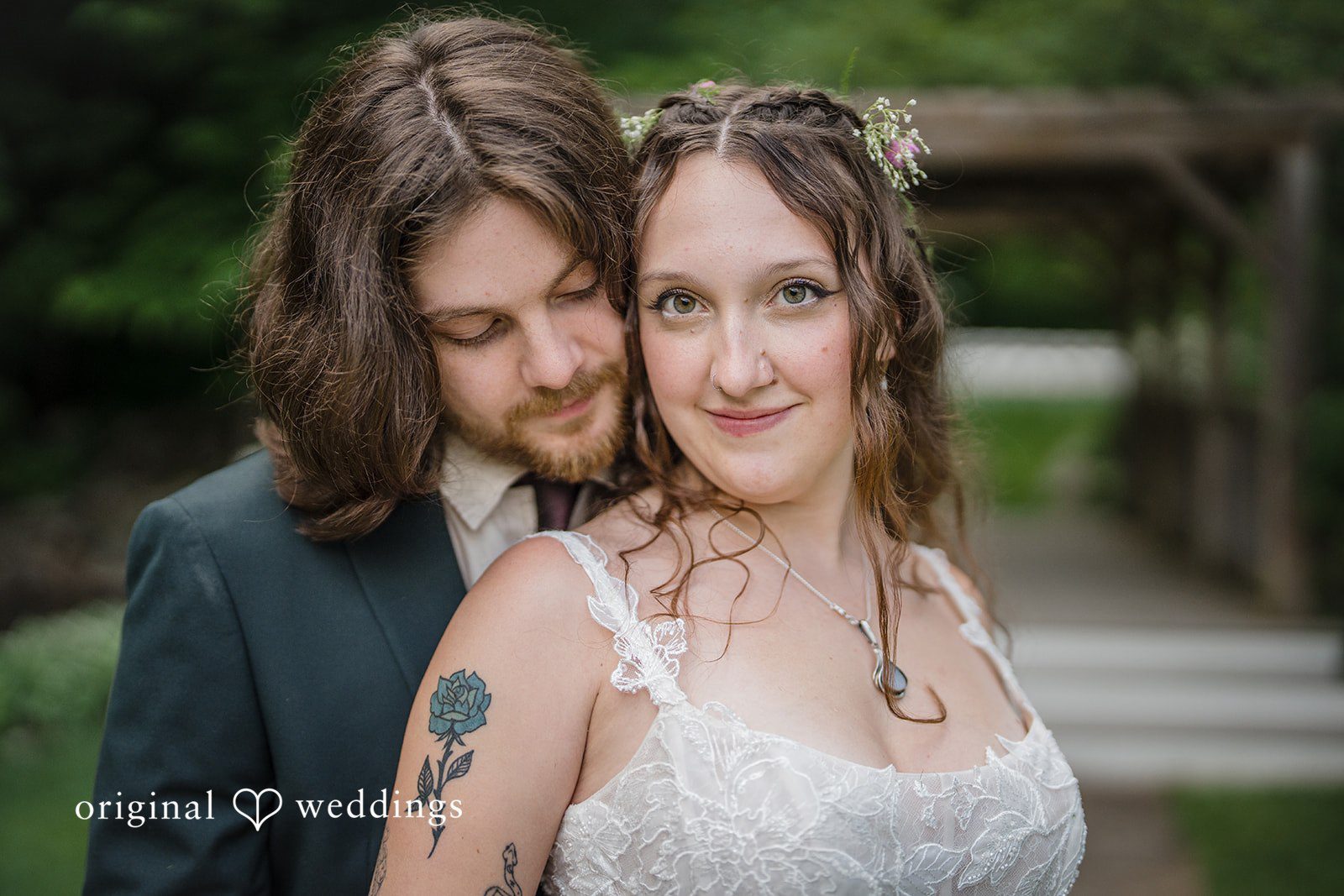 Meghan + Rowan A groom rests his chin near a smiling bride's shoulder as they pose closely together.