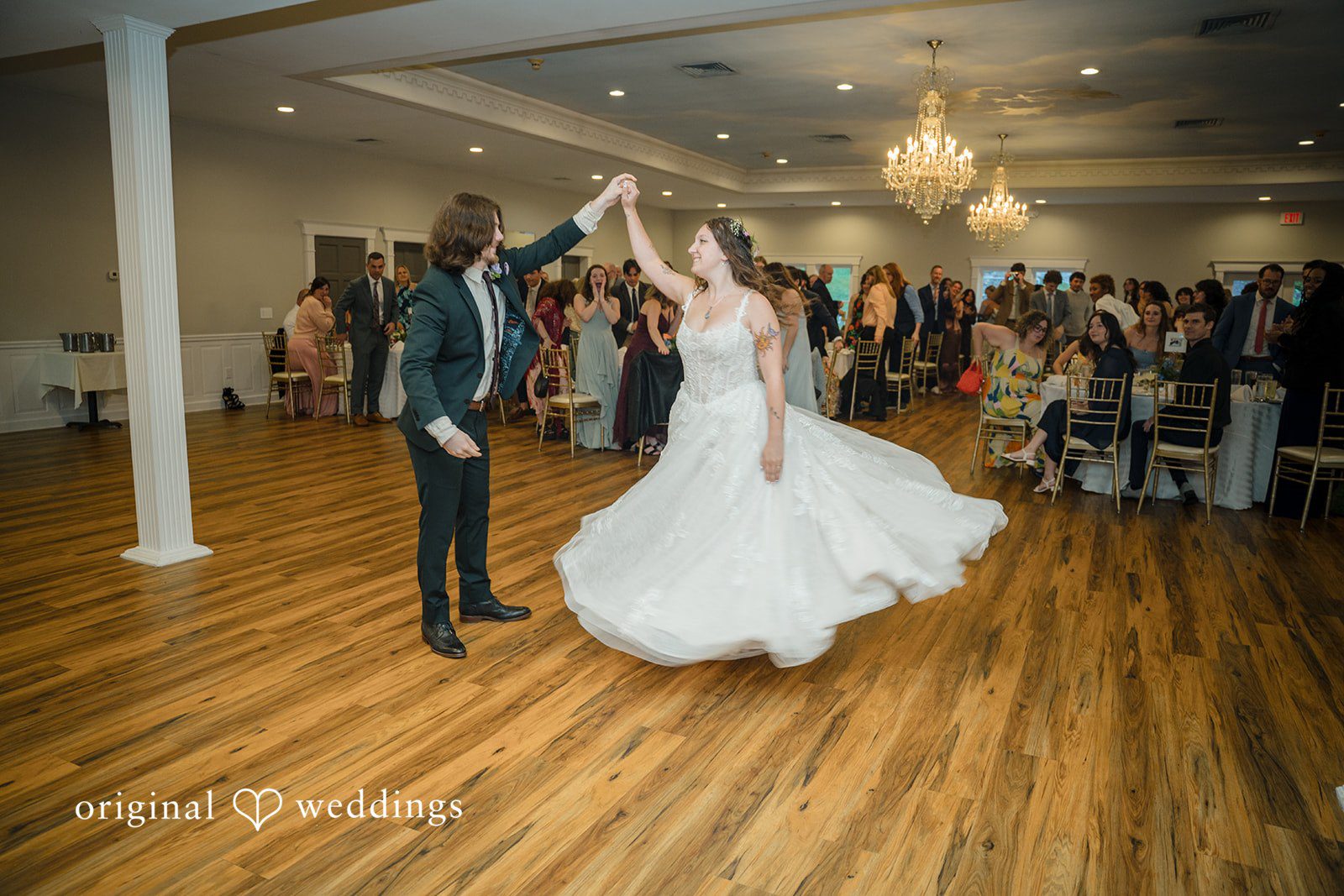 Meghan + Rowan A bride and groom dancing on a wooden reception floor as guests watch from the sidelines.