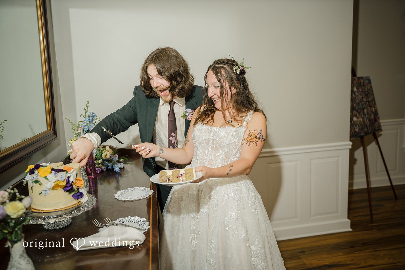 Meghan + Rowan A bride and groom cutting their wedding cake together at a reception table.