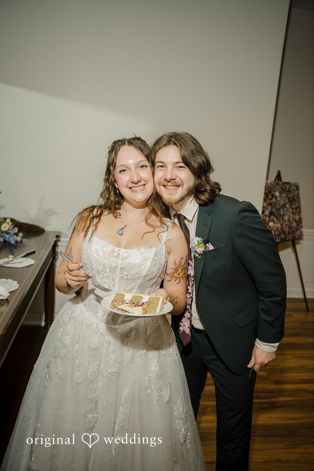 Meghan + Rowan A smiling bride and groom standing close together while the bride holds a plate with a slice of cake.