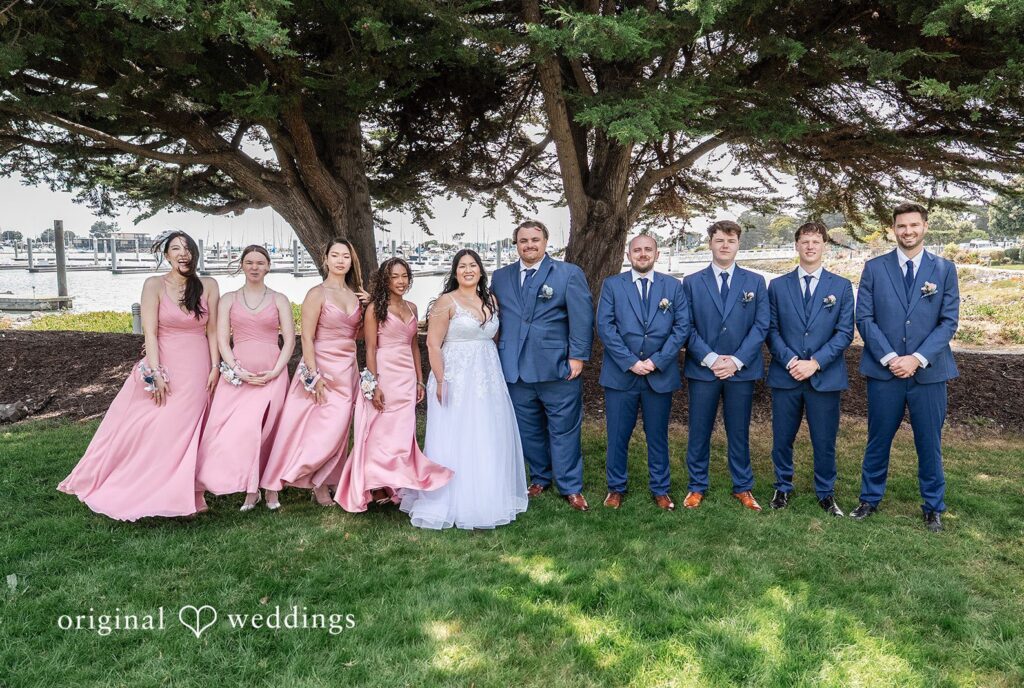 Thuy + Ryan Bride and groom posing with their bridesmaids and groomsmen beneath beautiful trees at Double Tree by Hilton Hotel Berkeley captured by San Francisco Wedding Photographers from Original Weddings.