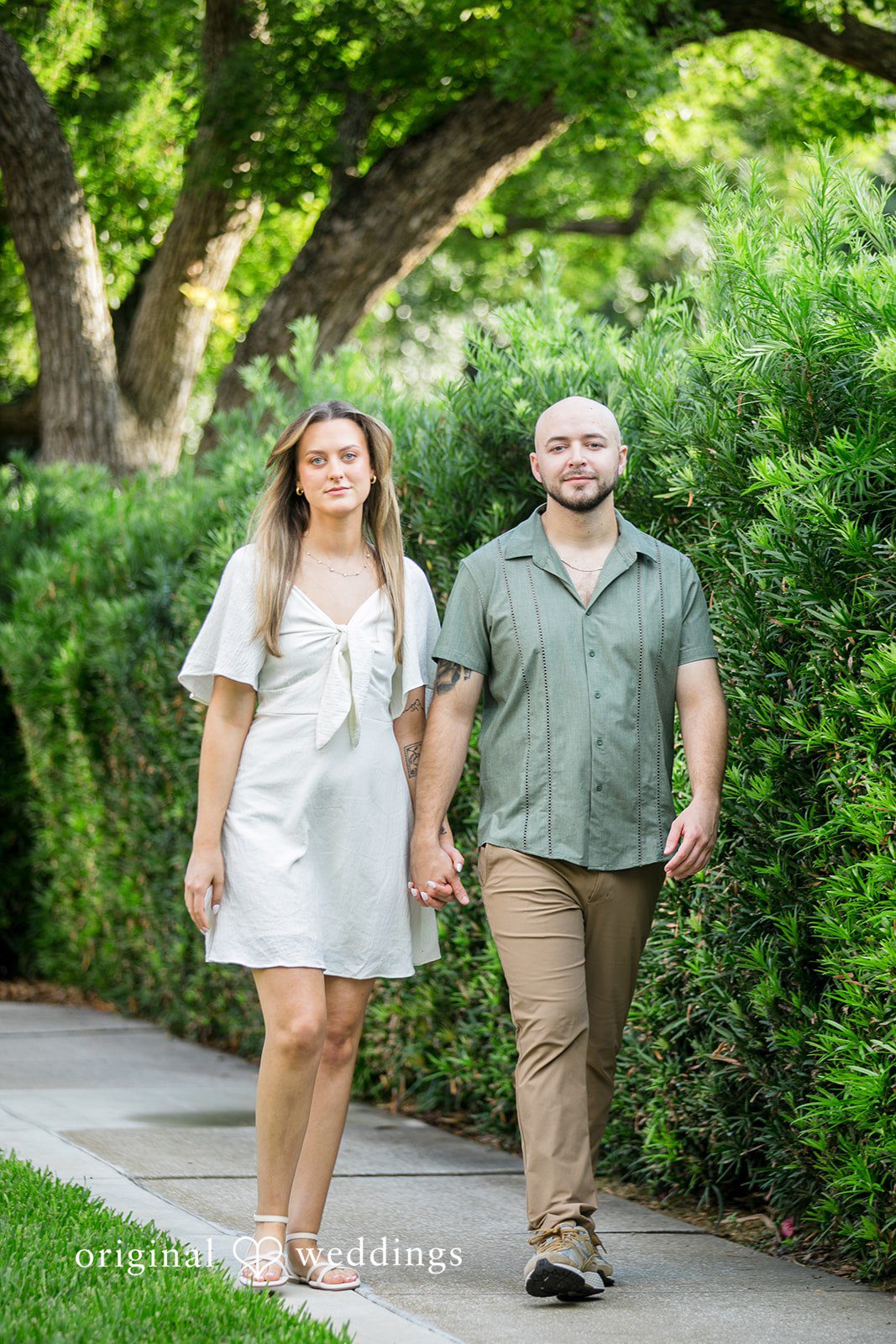 Lauren + Miles A couple strolling side-by-side down a green pathway.