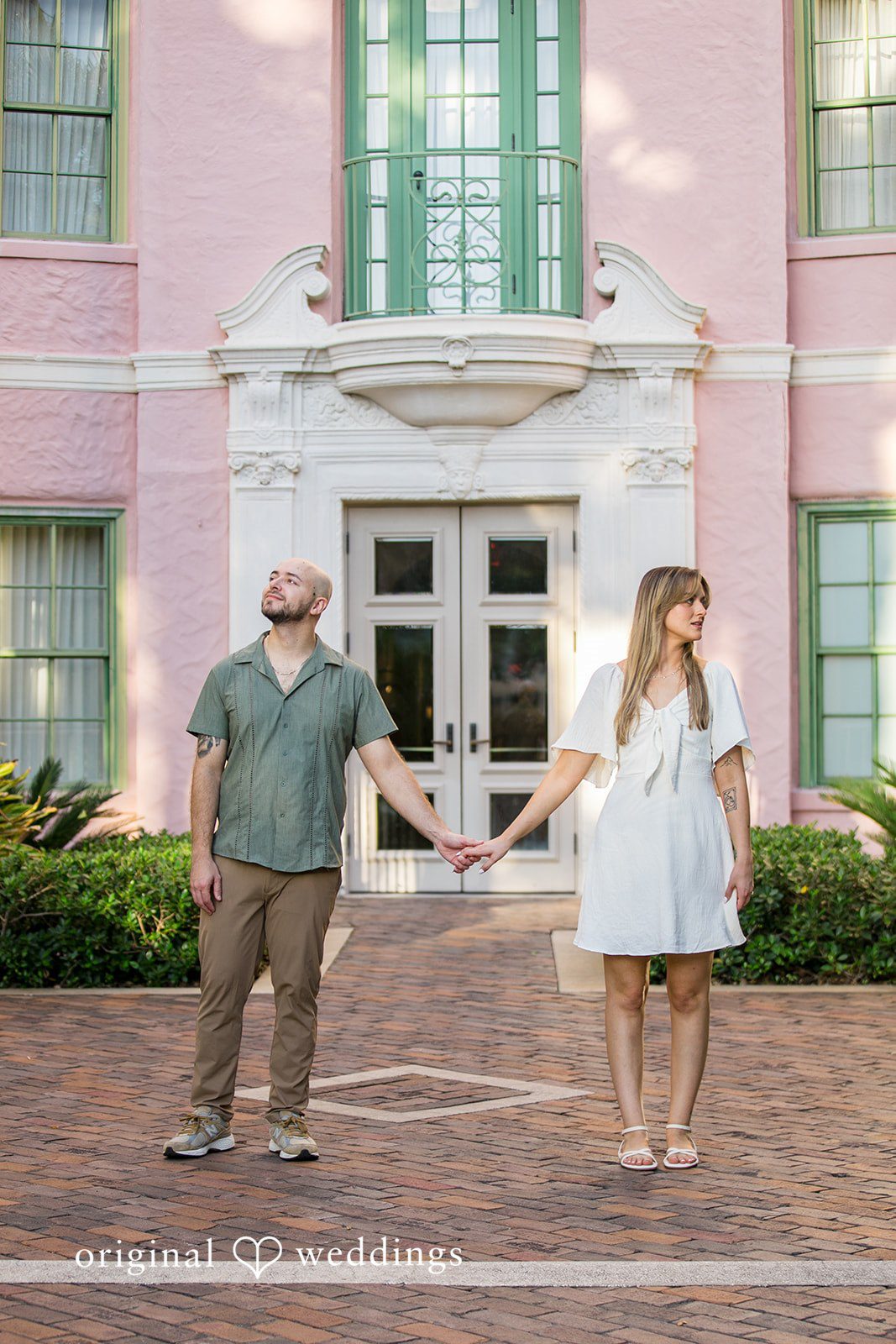 Lauren + Miles A couple walking past a light-colored building storefront.
