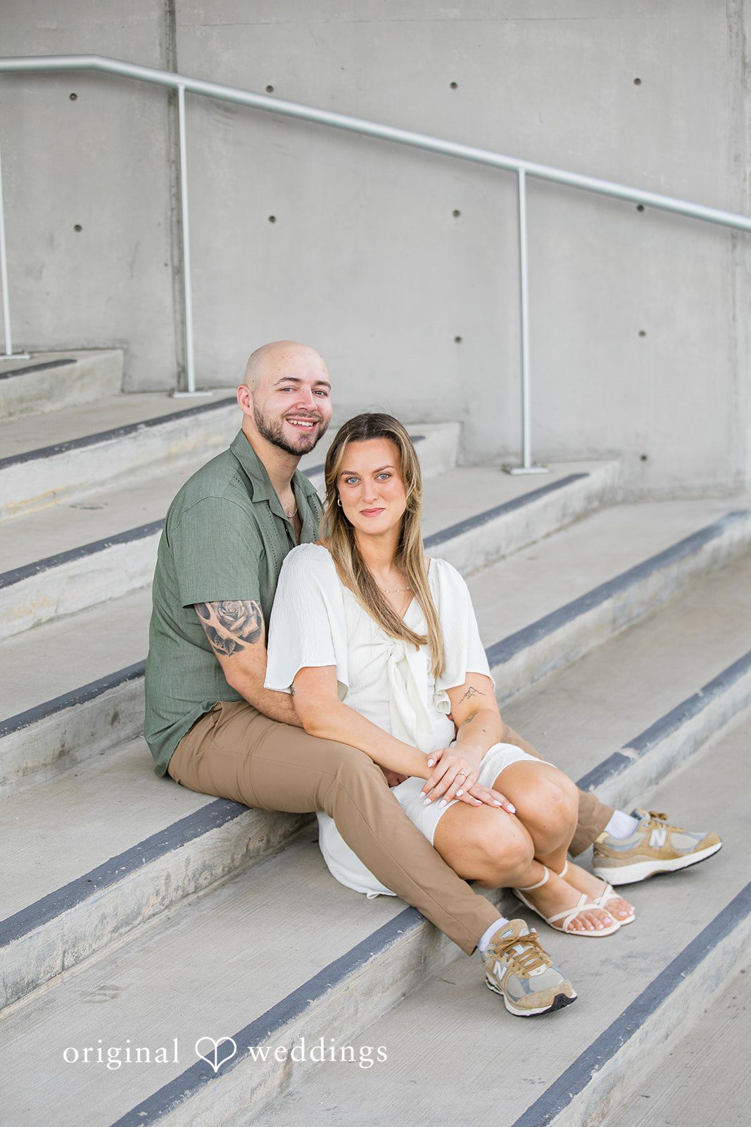 Lauren + Miles A couple sitting and smiling together on wide steps.