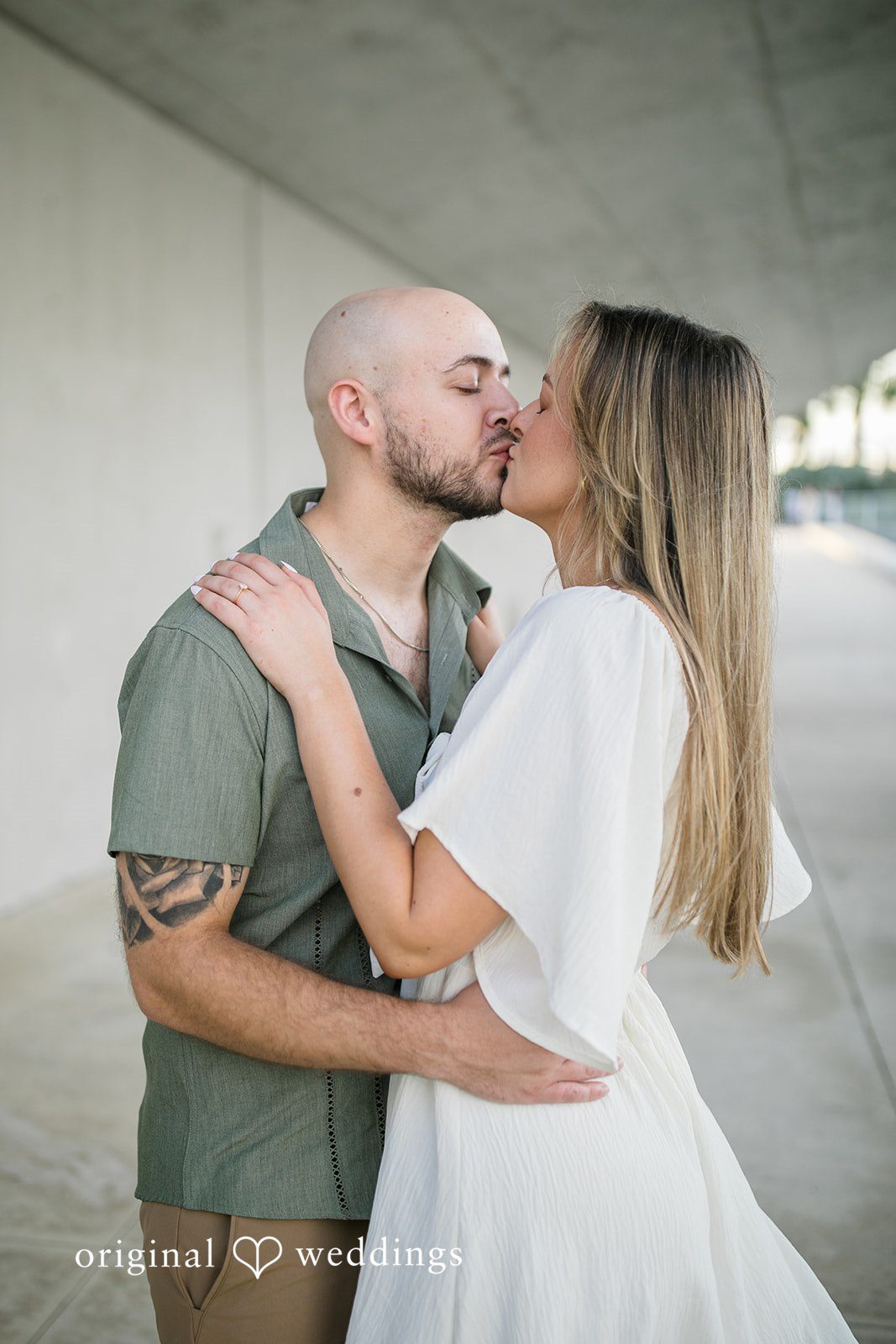 Lauren + Miles A couple sharing a kiss in front of a gray backdrop.