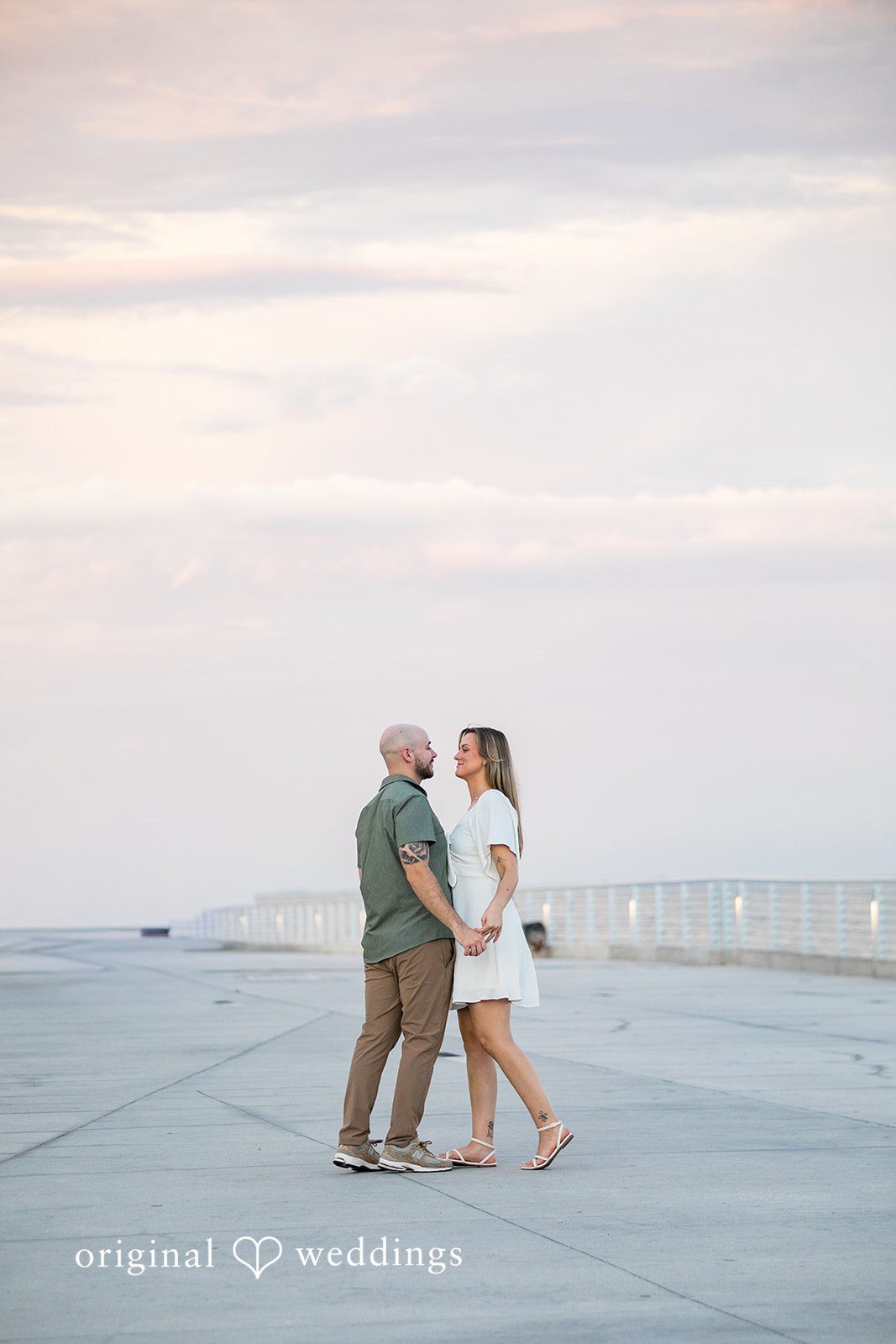 Lauren + Miles A distant shot of a couple holding hands on a wide pier.