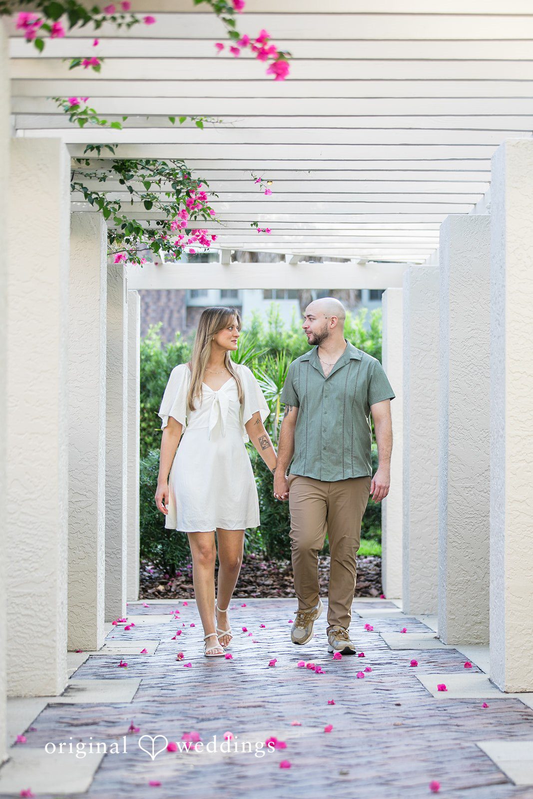 Lauren + Miles A couple walking hand-in-hand down a covered walkway.