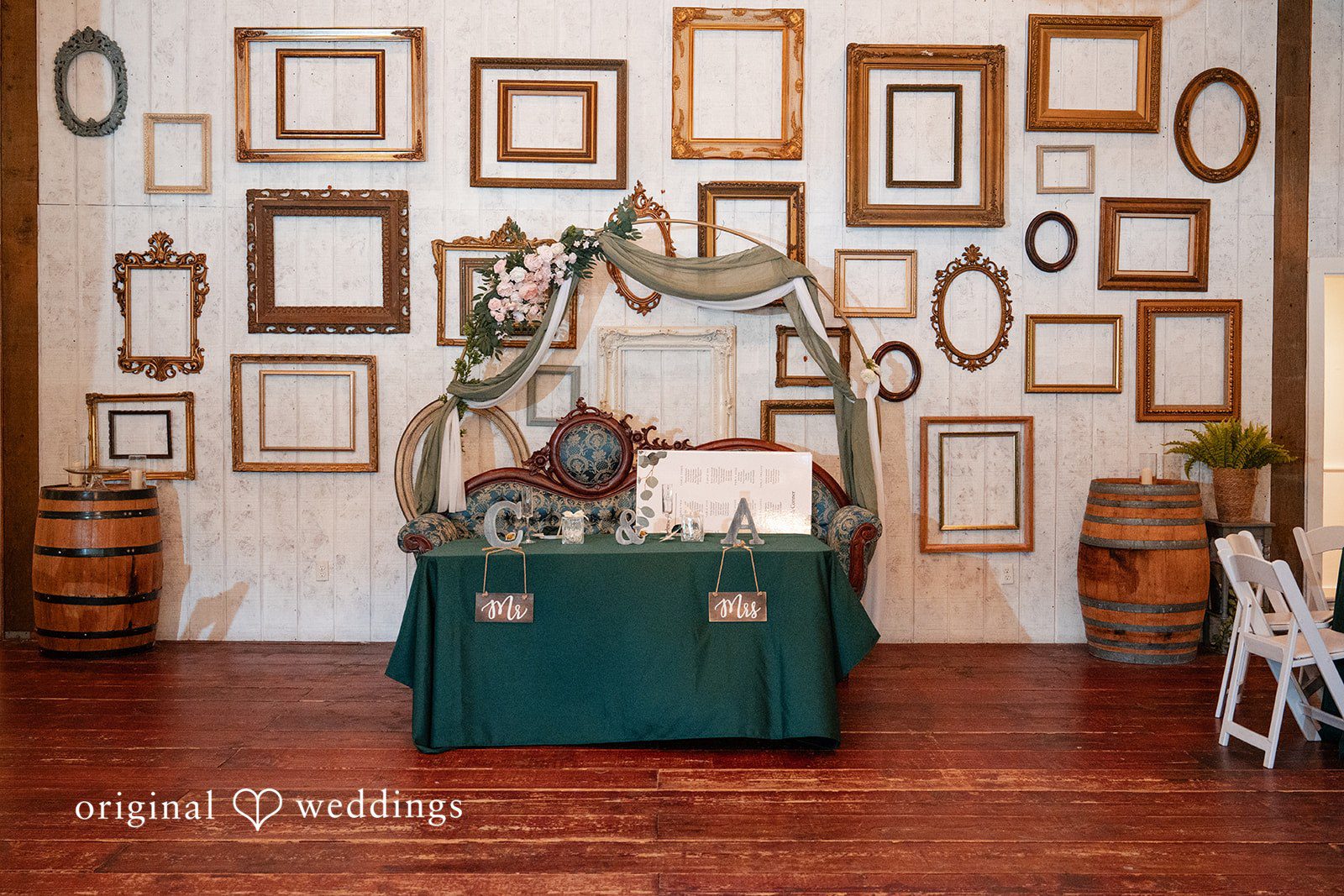 Conner + Ashley A guestbook table draped in green cloth positioned in front of a wall decorated with multiple empty picture frames.