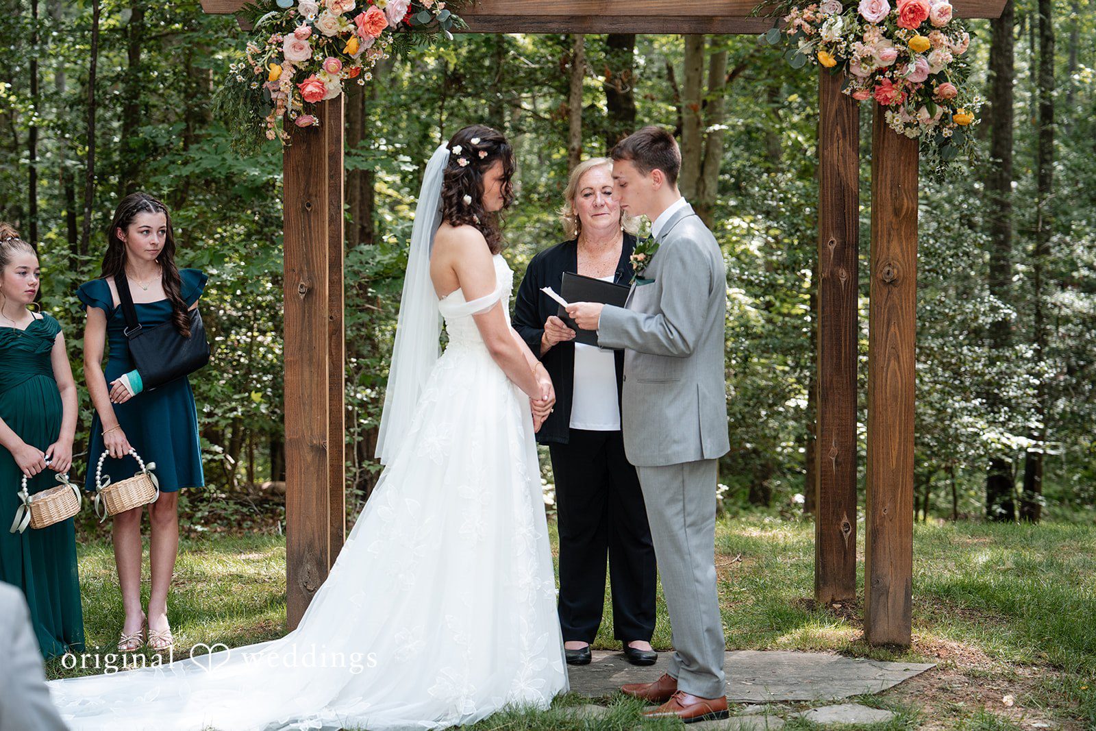 Conner + Ashley A bride and groom facing each other at a wooden altar while holding hands.