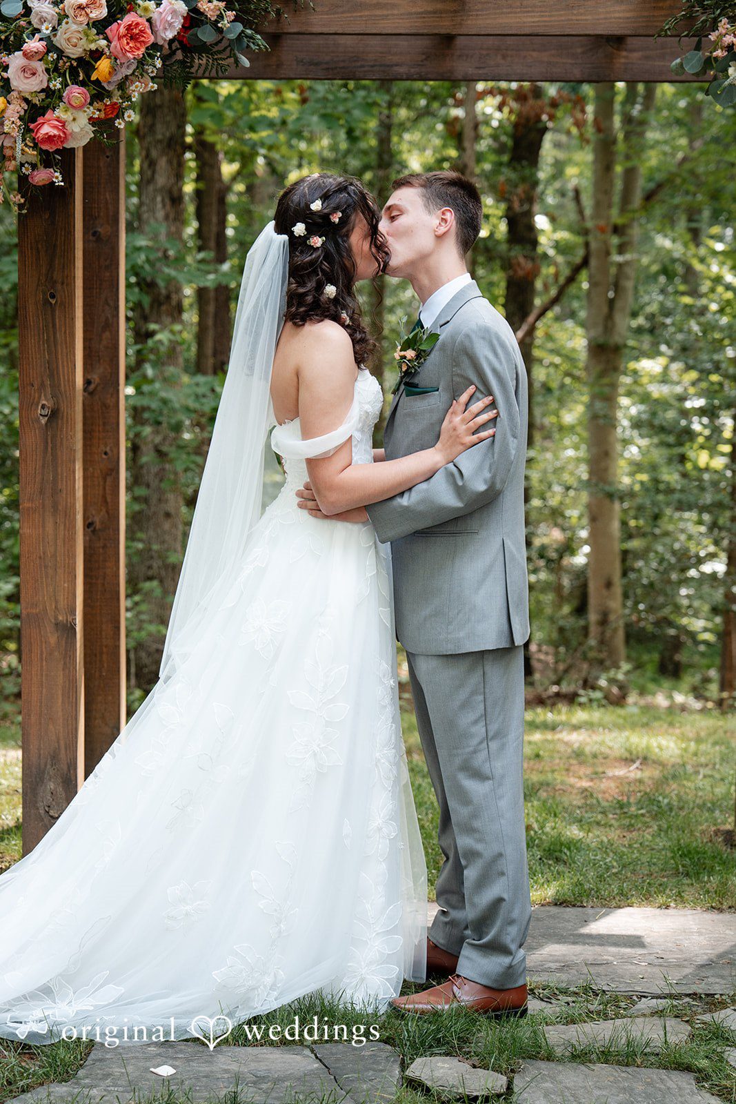 Conner + Ashley A bride and groom sharing a first kiss during their wedding ceremony.