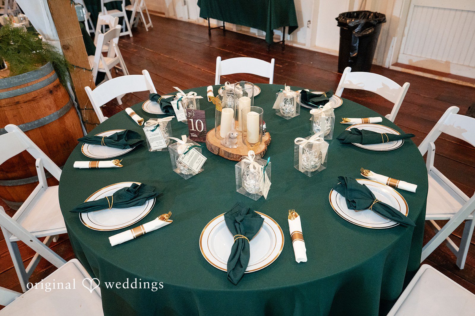 Conner + Ashley A round banquet table set with a dark green tablecloth, white plates, and matching green napkins.