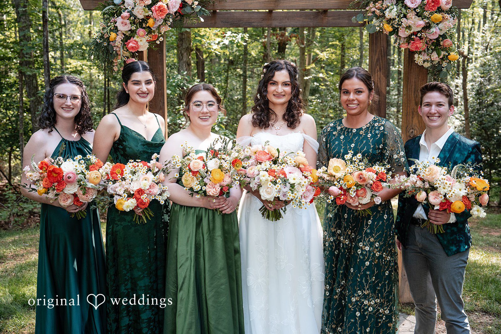 Conner + Ashley A bride standing with her bridesmaids who are wearing deep green and floral pattern dresses.